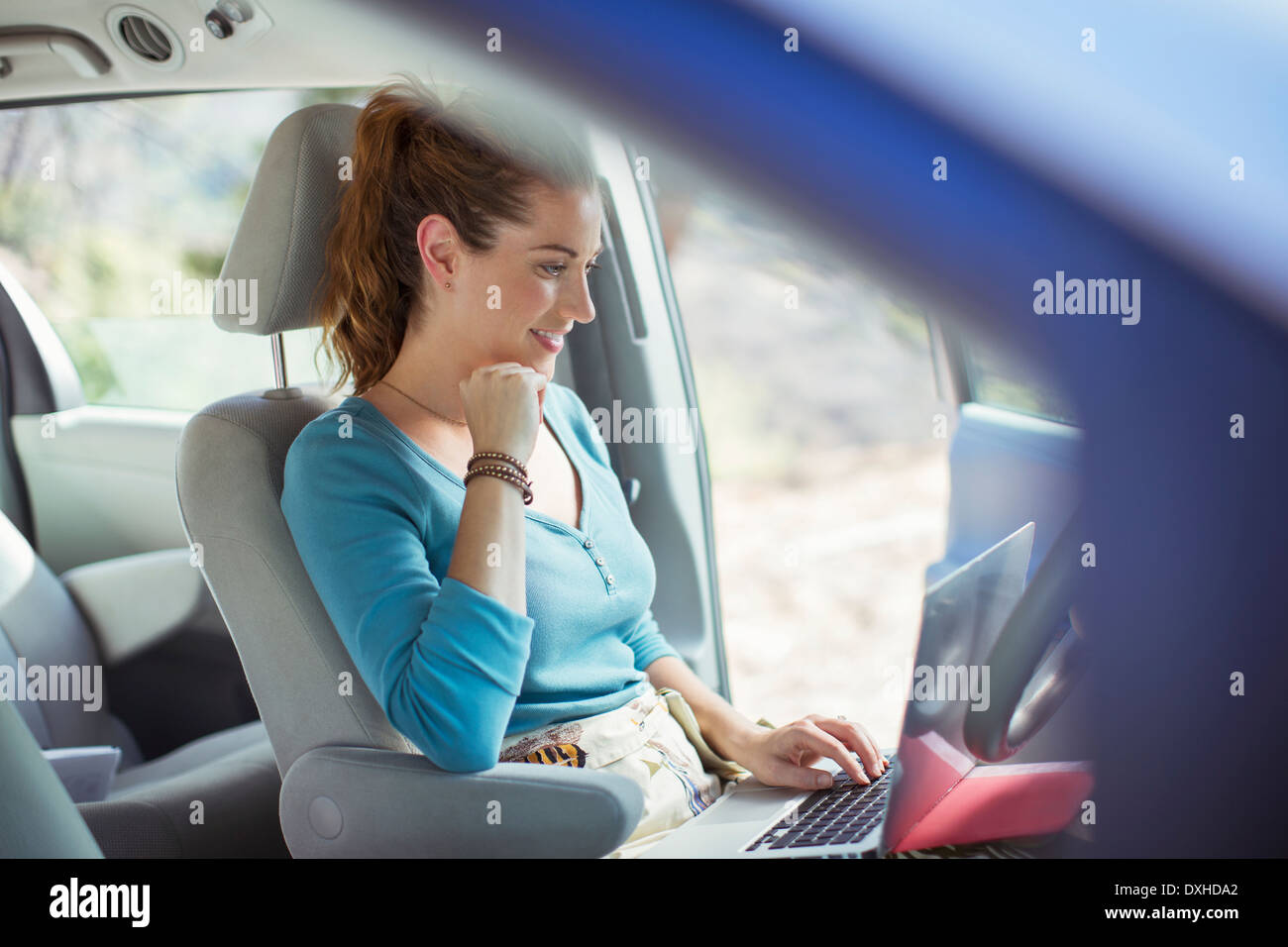 Frau mit Laptop im Auto Stockfoto