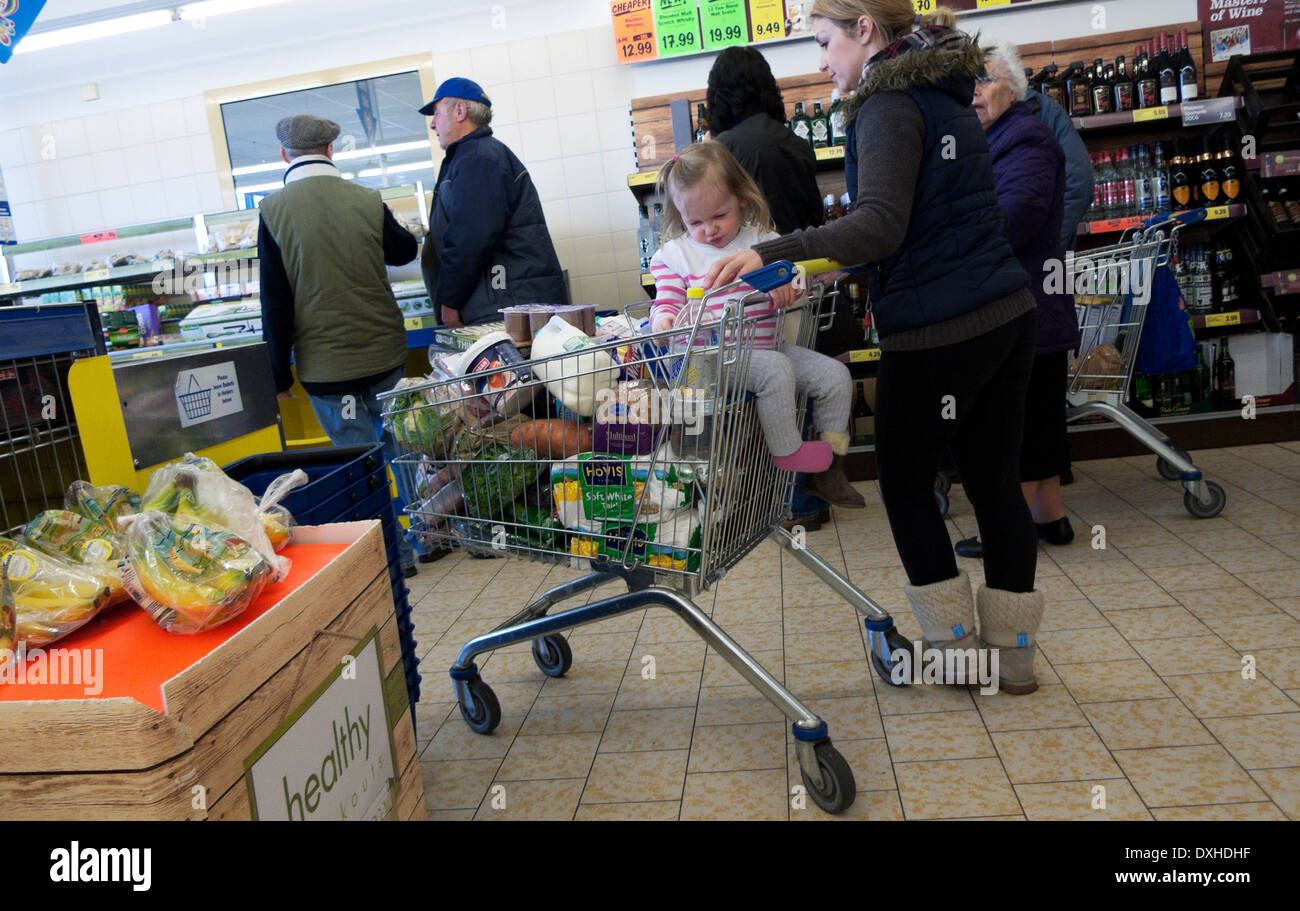 Eine Mutter und ein Kind im Lidl-Supermarkt, die einen vollen Trolley mit Lebensmitteleinkäufen in der Warteschlange stehen Großbritannien KATHY DEWITT Stockfoto
