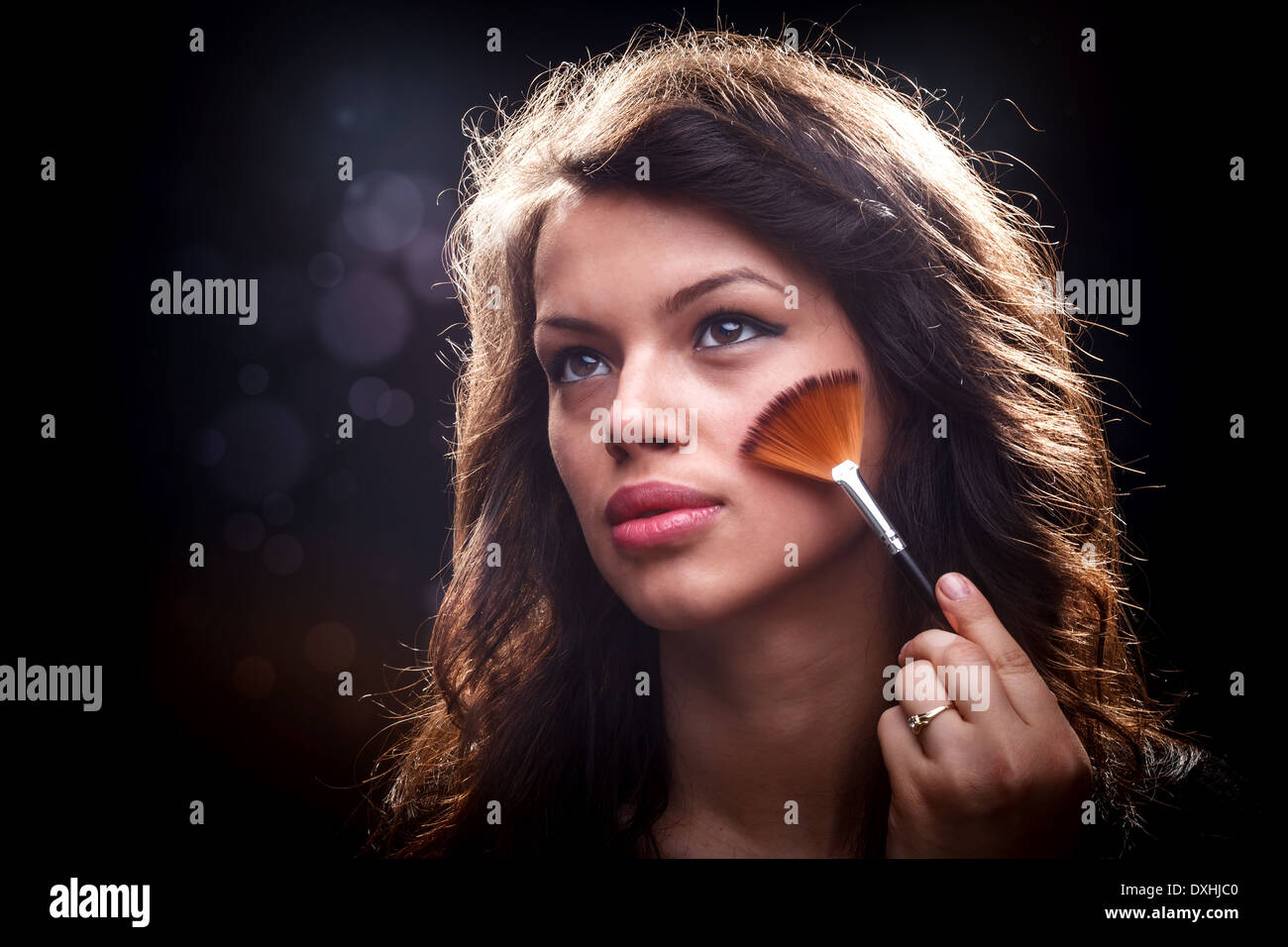 Junge Frau entfernen überschüssige Pulver mit Fächerpinsel Stockfoto