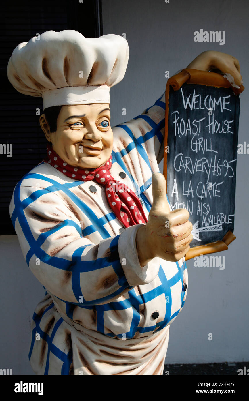 Riesen-Modell männlichen Küchenchef mit traditionellen Koch "´s Hut und Kleidung zu Zwinkern und zeigt Daumen hoch halten Menü, UK Stockfoto