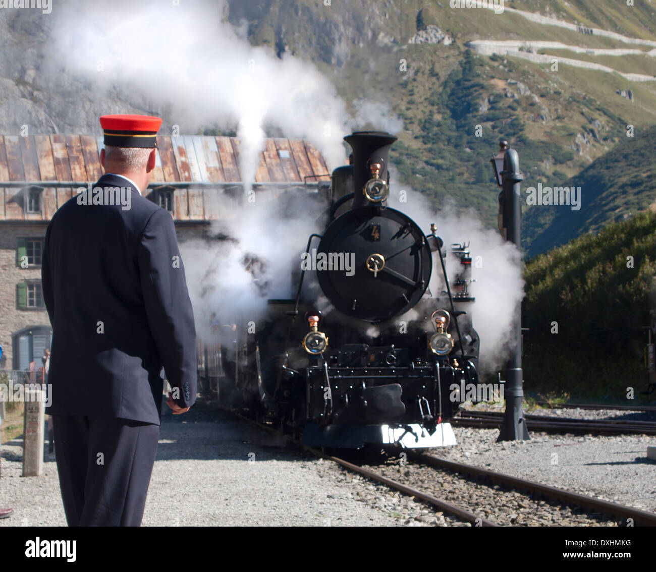 Der historische Dampfzug der Furka stoppt bei Gletsch, Schweiz, in den Alpen 1760m über dem Meeresspiegel, um neue Kohle und Wasser kostenlos. Stockfoto