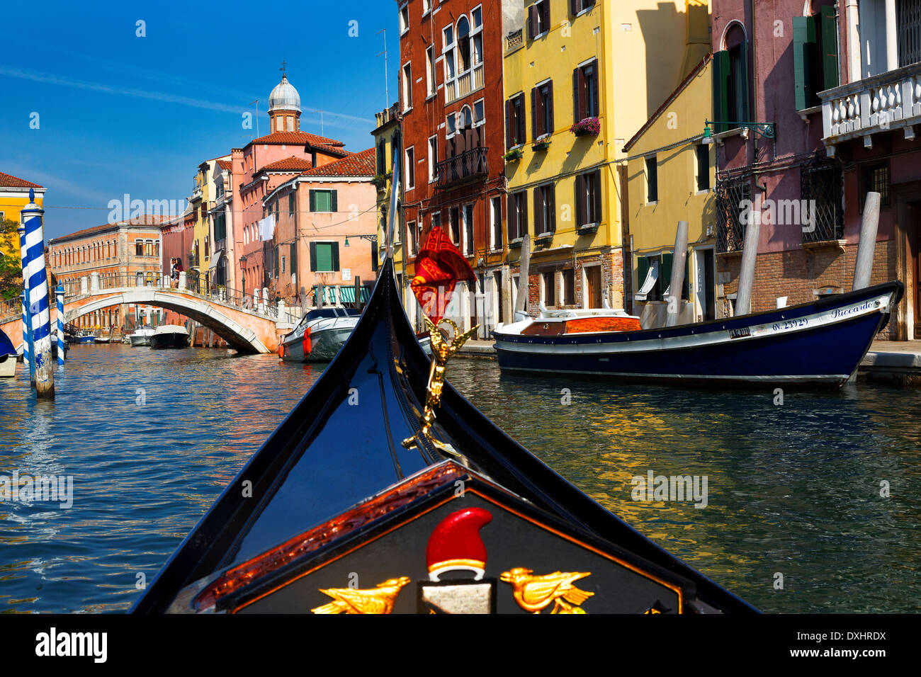Gondel Fahrt Blick auf bunte Kanal, strahlend blauer Himmel, festgemachten Schiffe und Gebäude in Venedig, Italien Stockfoto