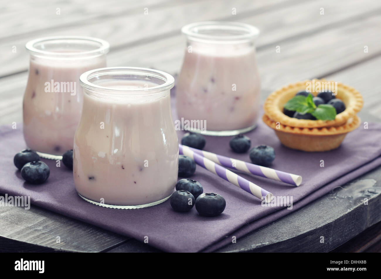 Joghurt mit Reife frische Heidelbeeren in Gläsern auf hölzernen Hintergrund Stockfoto