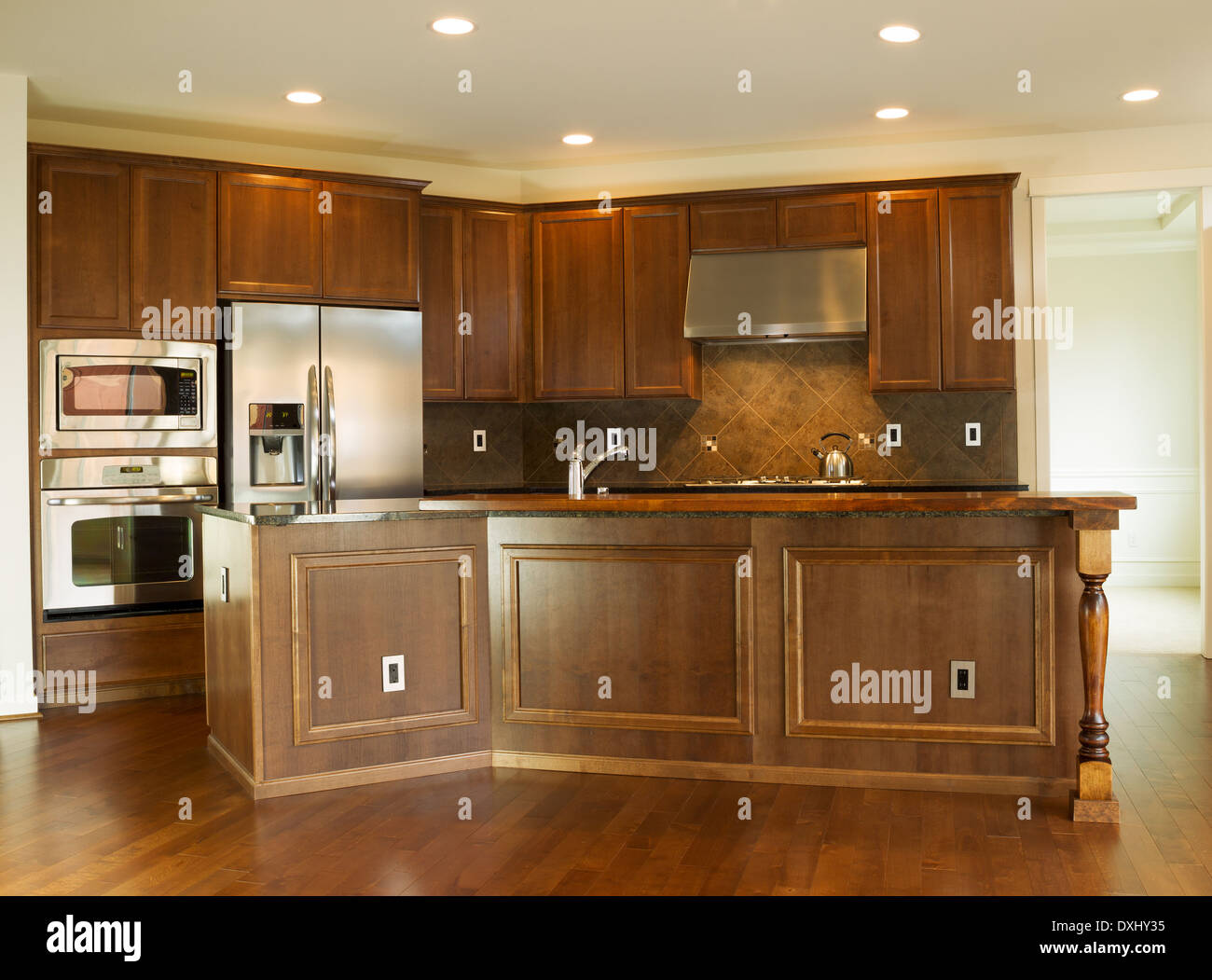 Horizontale Foto von einer modernen Wohnküche mit steinernen Gegenoberseiten, Edelstahlgeräte, Kirsche Holz Schränke Stockfoto