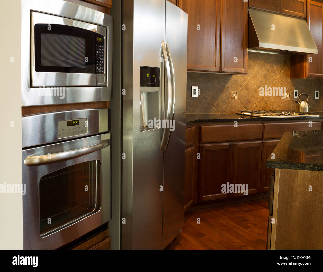 Nahaufnahme Foto von einem Edelstahlgeräte in moderne Wohnküche mit steinernen Gegenoberseiten und Kirsche Holz Schränke Stockfoto