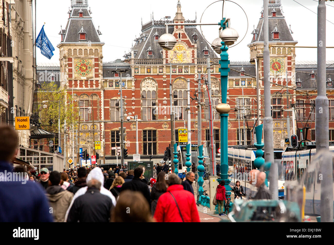 Fußgänger zu Fuß entlang Damrak in Amsterdam. Der Bahnhof Centraal ist im Hintergrund. Stockfoto