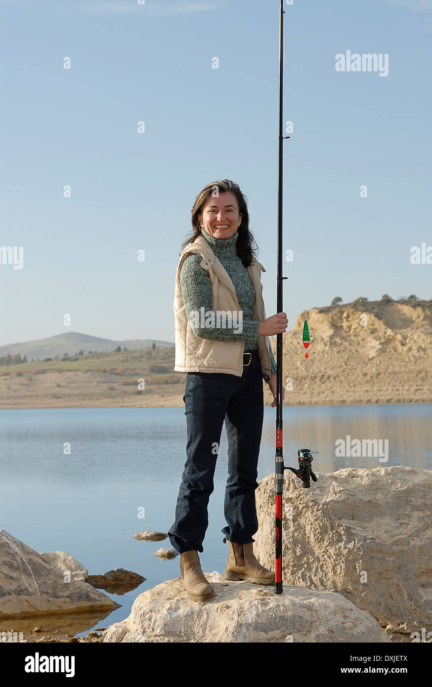 Reife Frau am Seeufer mit Angelrute, Lächeln, Porträt Stockfoto