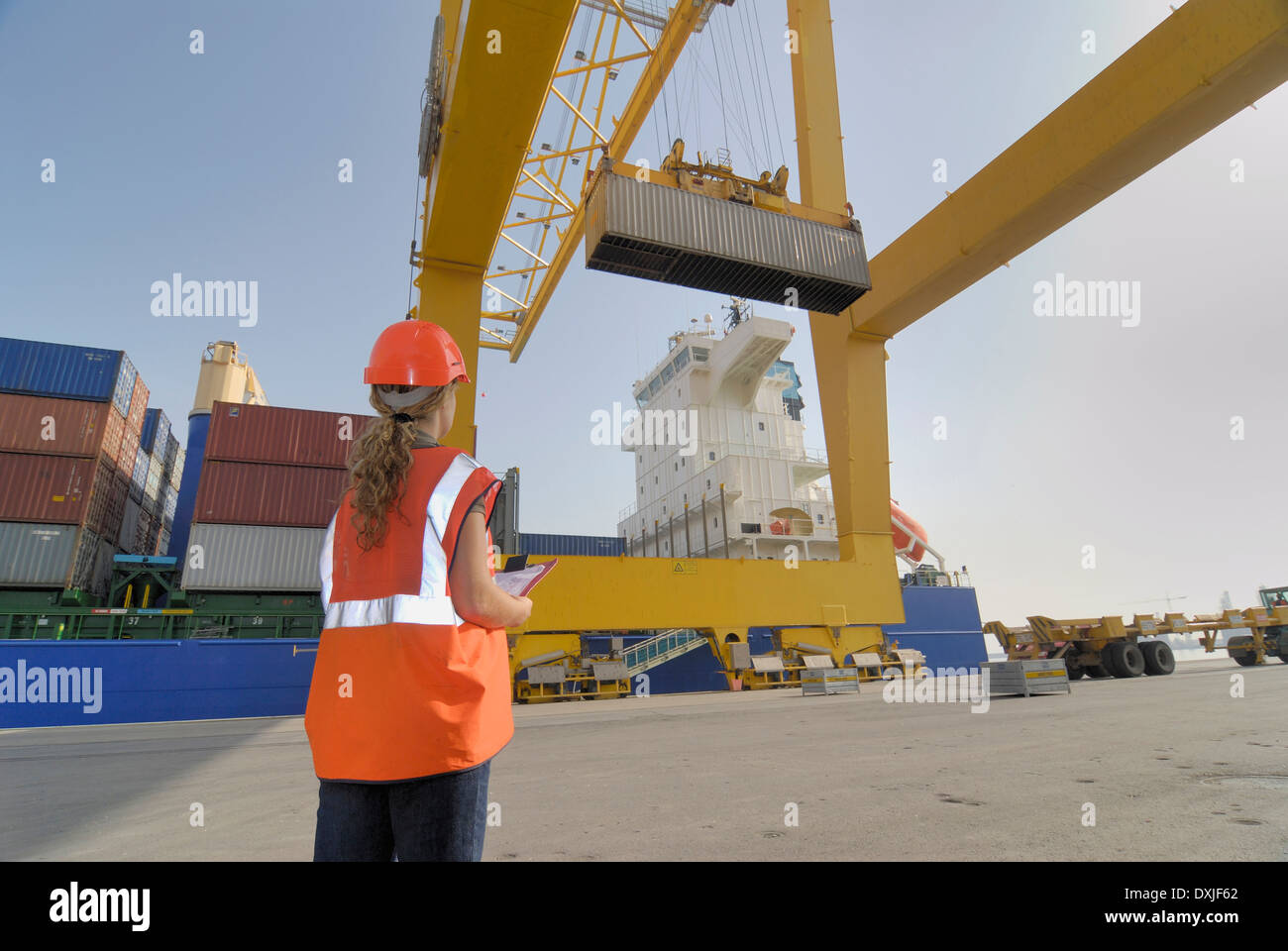 Frau am Hafen beobachten Container auf Straddle carrier Stockfoto