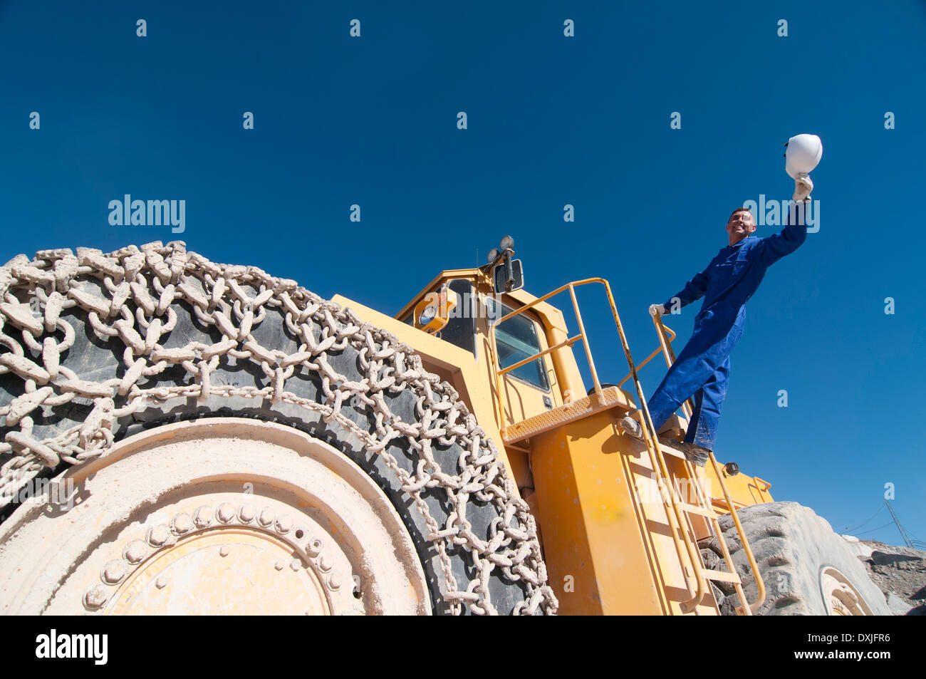 Arbeiter winken Schutzhelm stehend auf Bergbau-Maschine Stockfoto