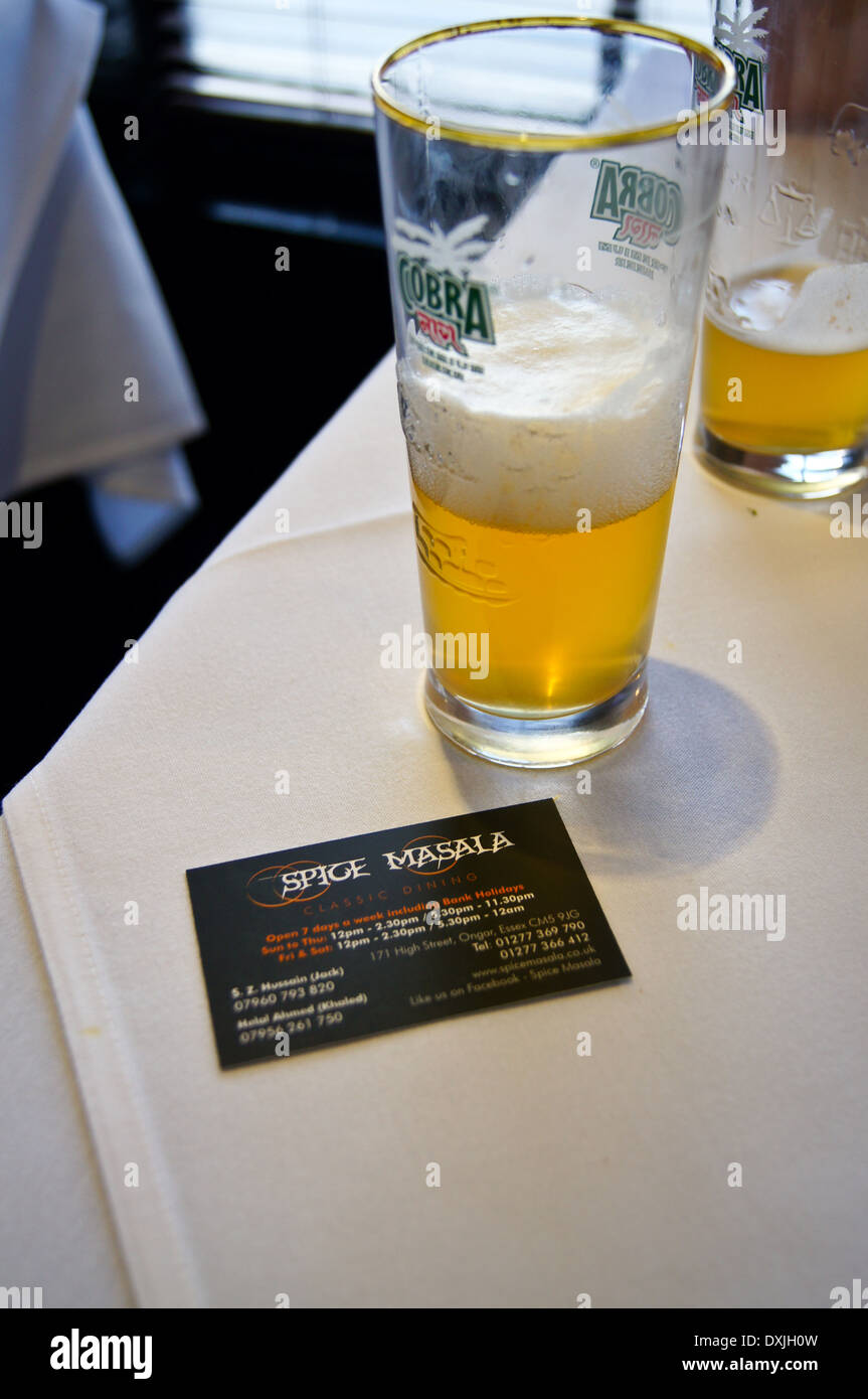 Ein Glas Cobra Bier und Business card Spice Masala Indischen Restaurant, früher Kismet Tandoori, Chipping Ongar, Essex, England pub Tabelle Getränke Glas Stockfoto