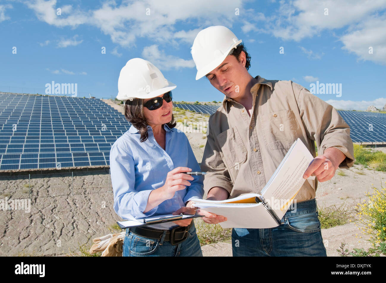 Ingenieure, die Pläne in Solaranlage betrachten Stockfoto