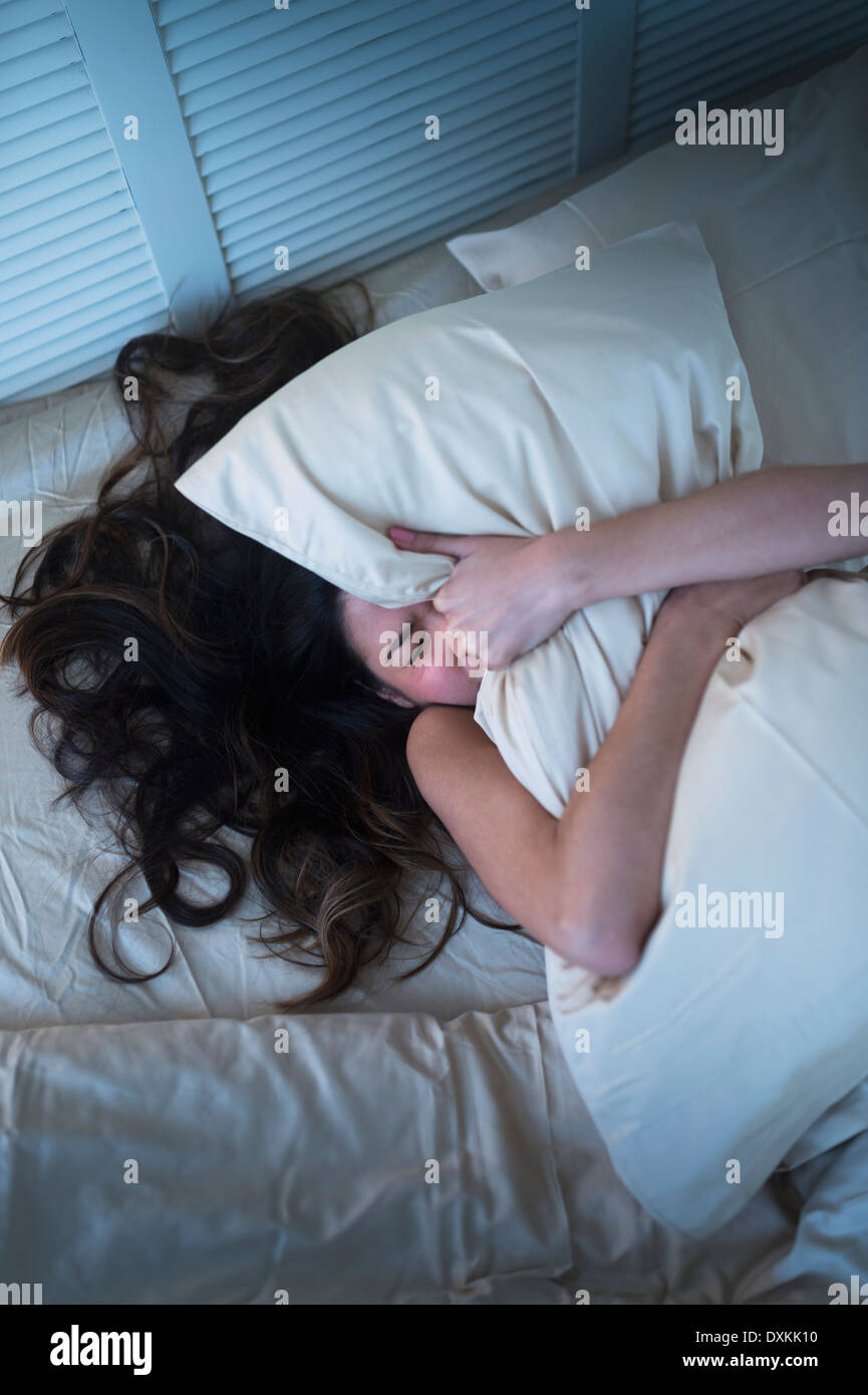 Frustriert Hispanic Frau greifen Kissen im Bett Stockfoto