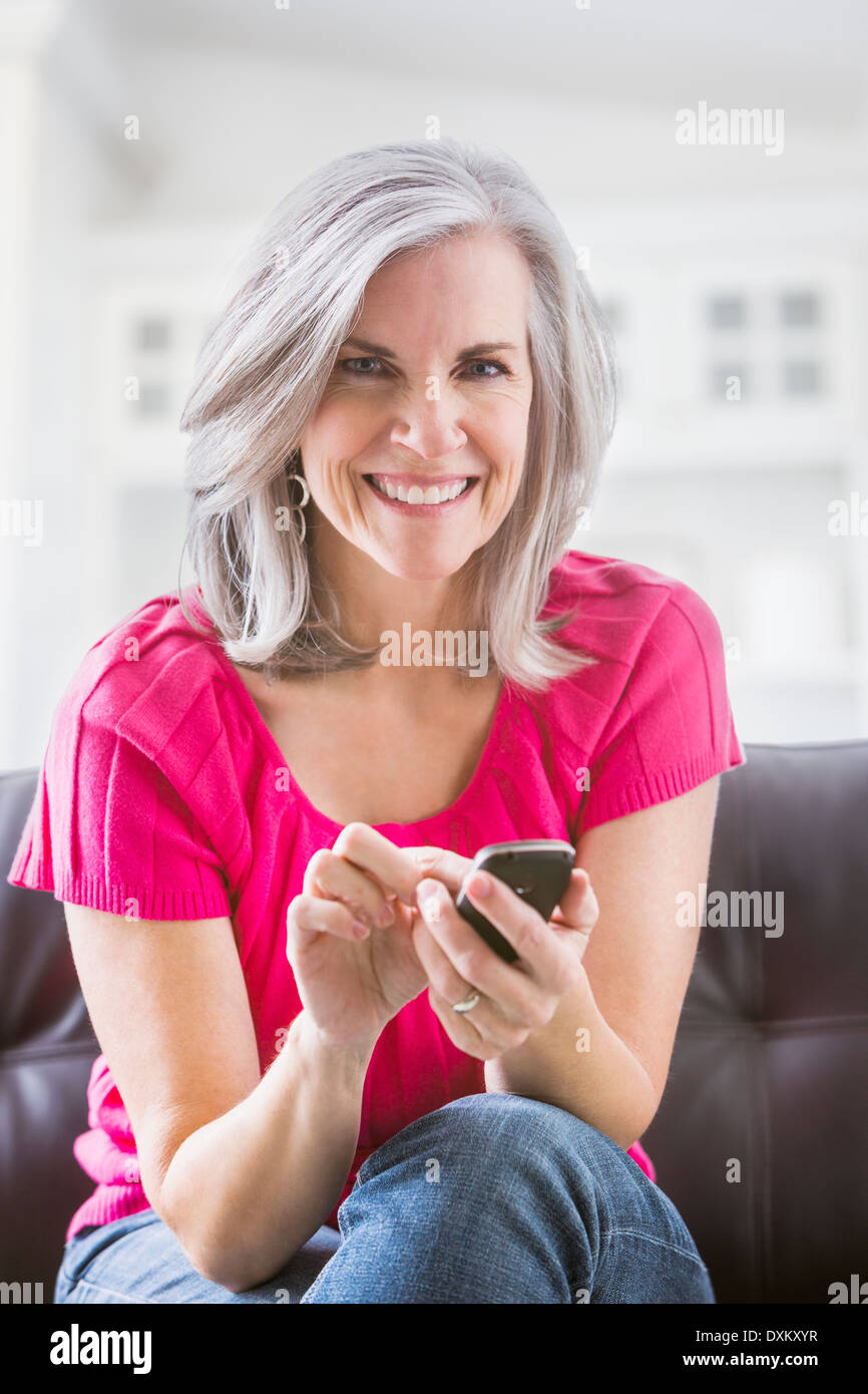 Porträt des Lächelns kaukasischen Frau Textnachrichten auf sofa Stockfoto