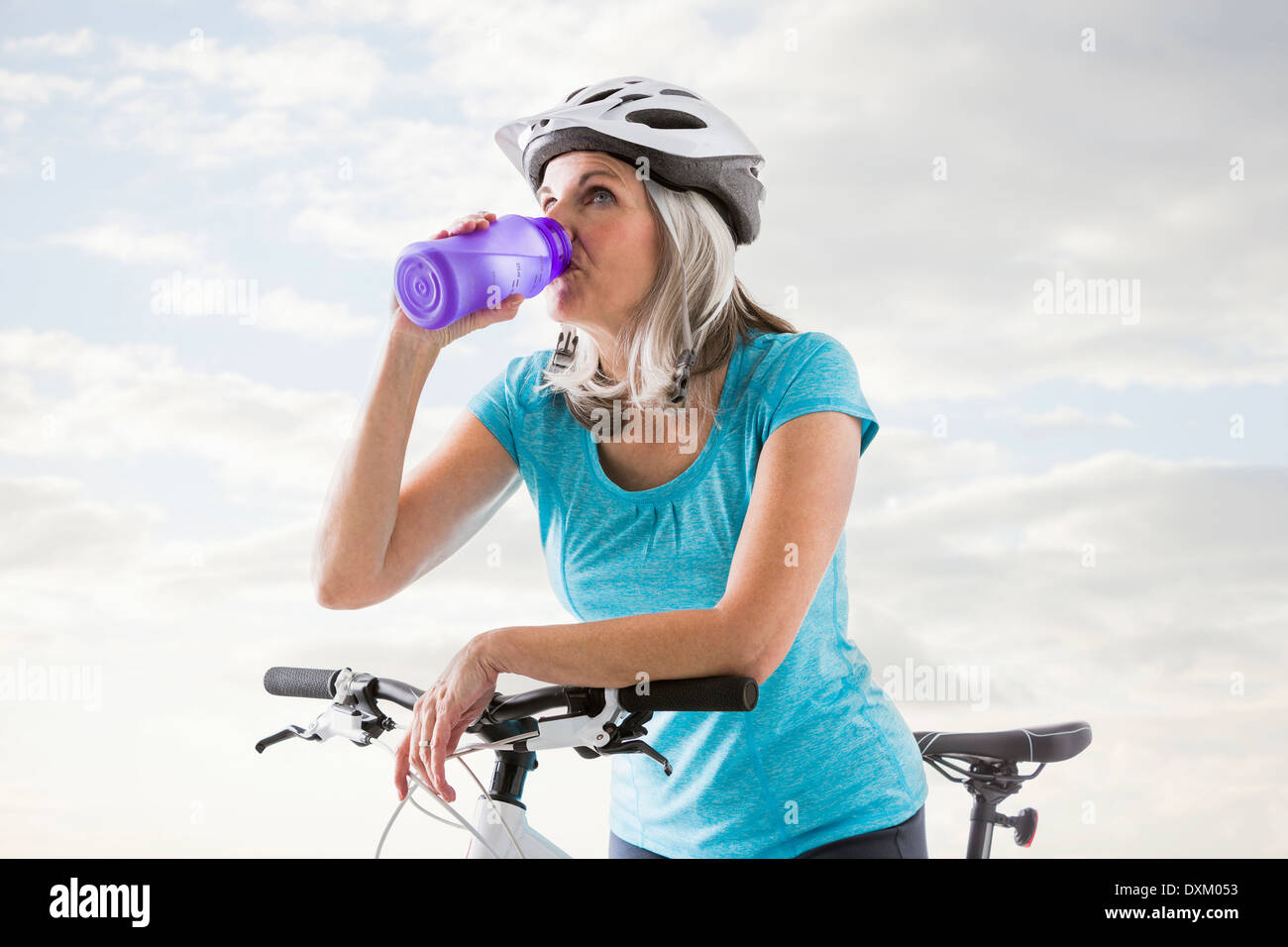 Kaukasische Frau trinkt aus Flasche Wasser auf dem Fahrrad Stockfoto