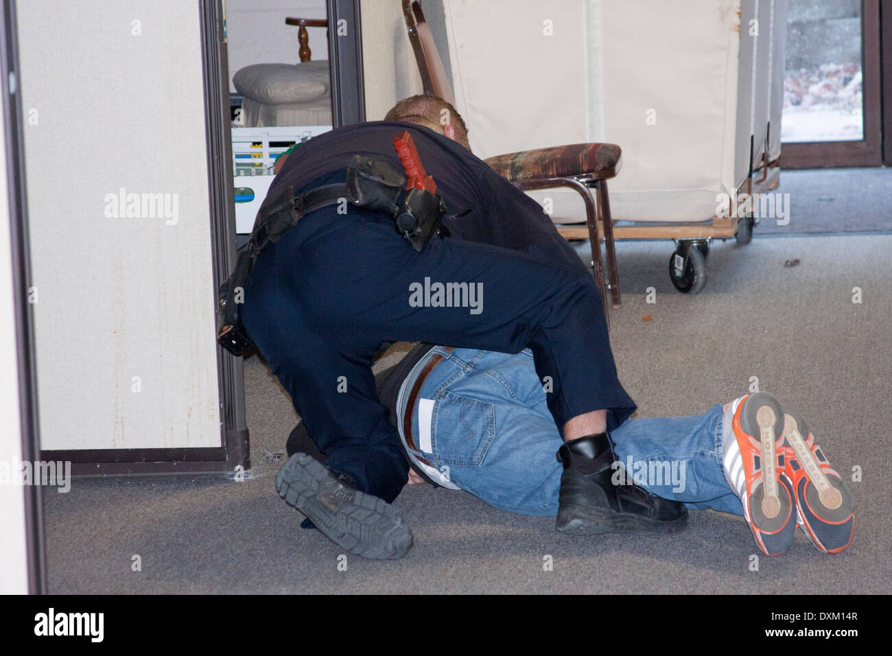 Ein Slinger Polizei-Offizier Erfassung ein schießendes Verdächtigen in einer Schule während einer Übung Stockfoto