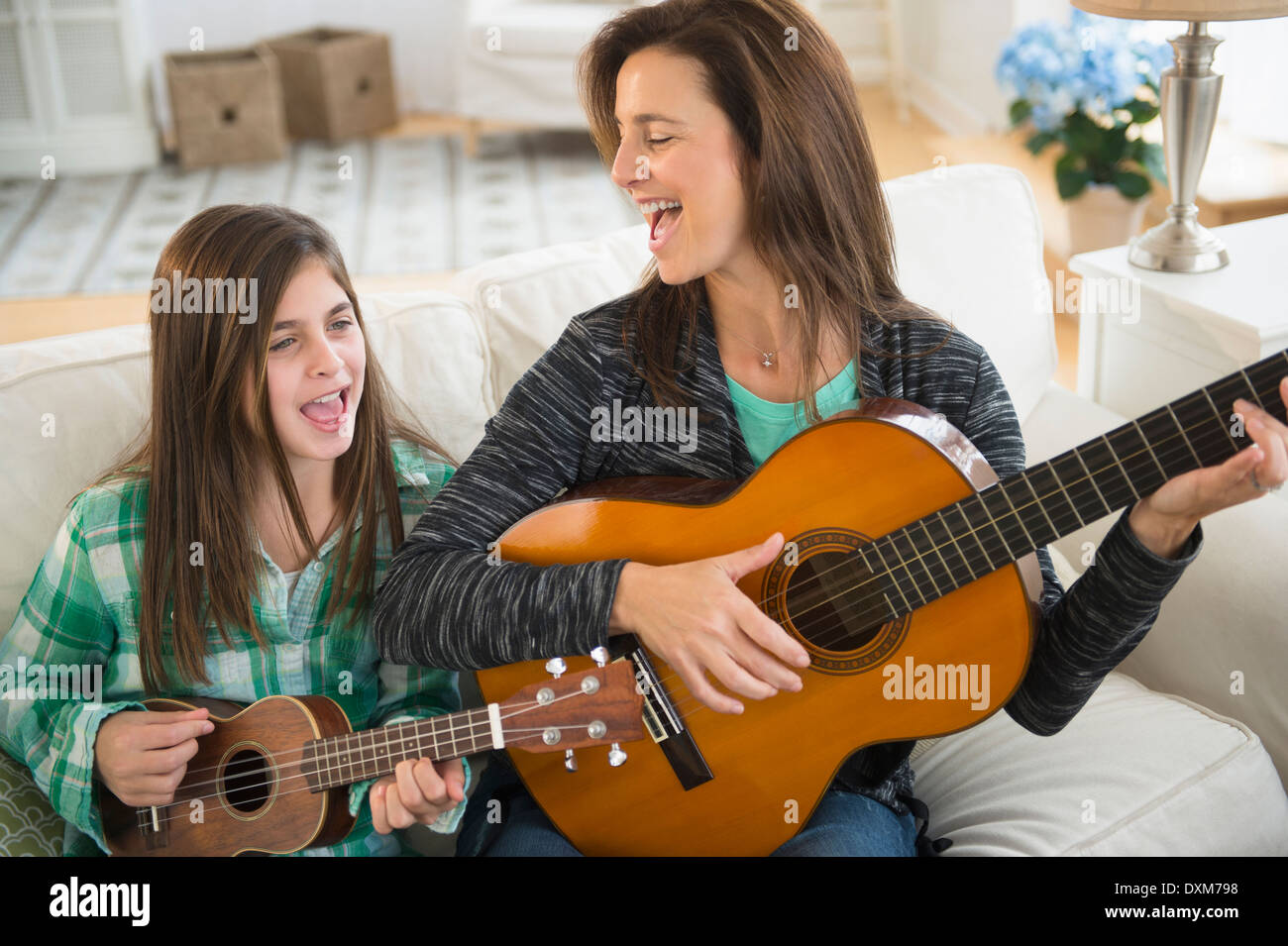 Kaukasische Mutter und Tochter singen mit Gitarre und ukulele Stockfoto