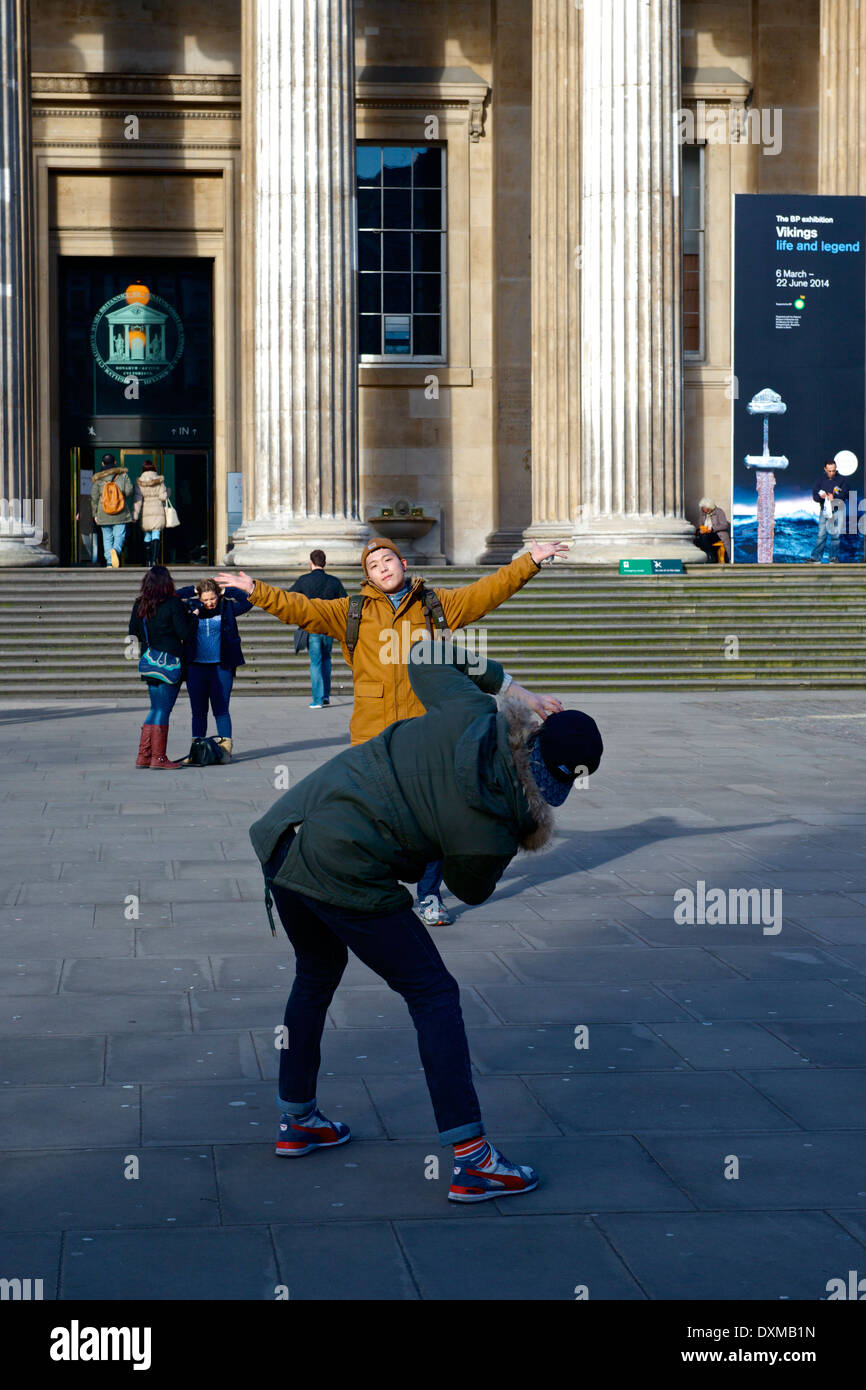 Oriental ein Mann posiert mit seinen ausgestreckten als sein Begleiter sein Foto außerhalb des British Museum in London nimmt Stockfoto