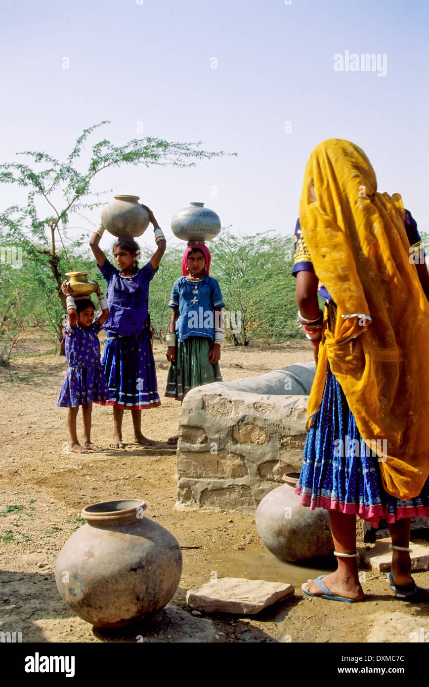 Indische Frauen sammeln Wasser in Flaschen, Gläser auf dem Kopf tragen Stockfoto