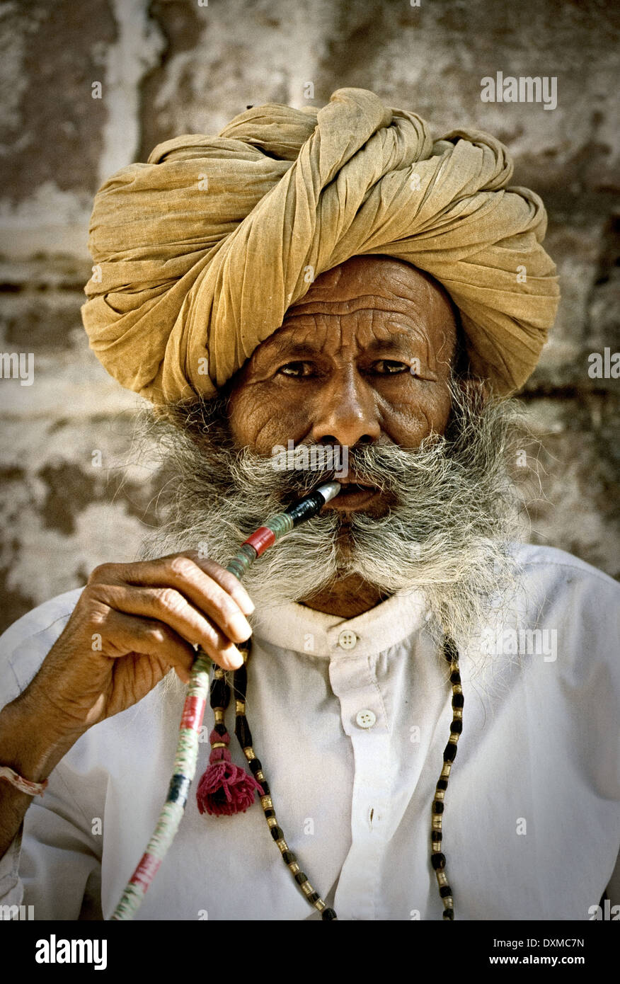 Älterer grau-bärtiger Mann mit gelber Turban Rauchen einer Wasserpfeife in Mehrangarh Fort in Jodhpur, Indien. Digital manipulierte Bild. Stockfoto