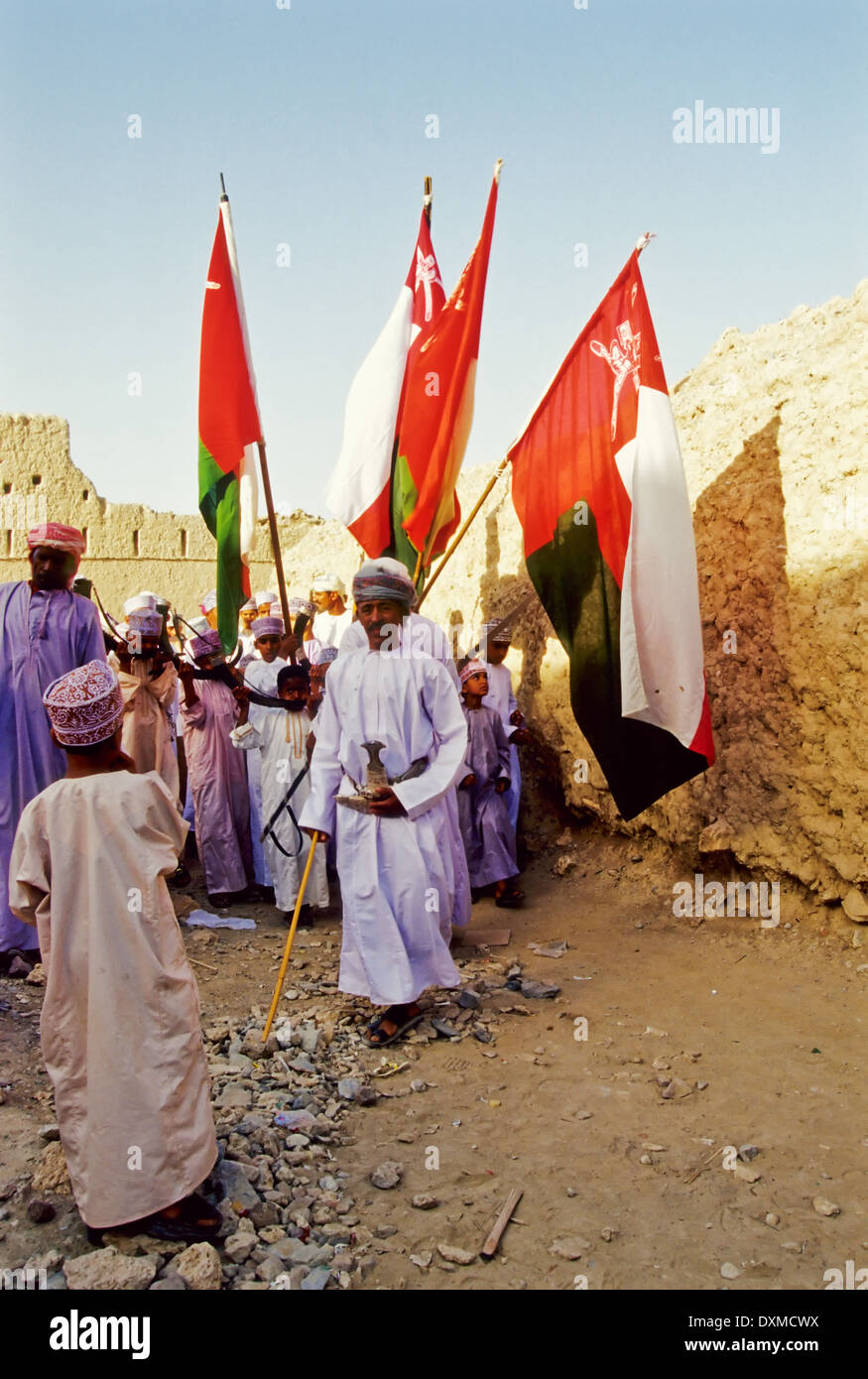 Omanische Männer in einer Prozession mit omanischen Fahnen bei den Eid al-Fitr Feierlichkeiten in Fanja, Oman Stockfoto