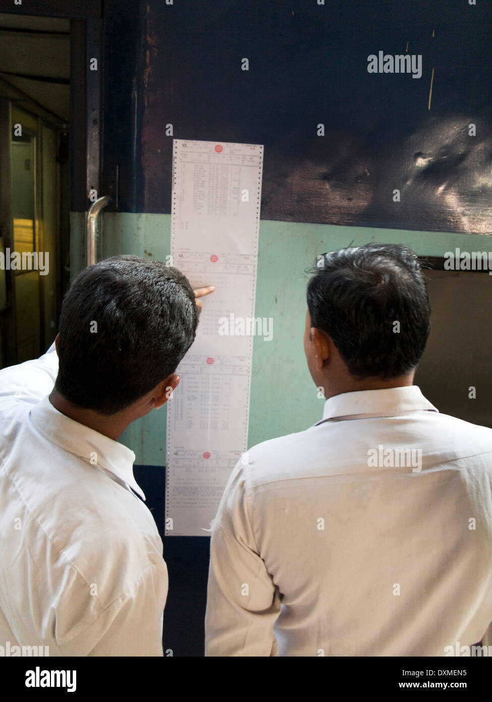 Indien, Reisen mit der Bahn, Jammu Bahnhof, zwei Männer, die Überprüfung Reservierungsliste auf Seite des Zuges eingefügt Stockfoto