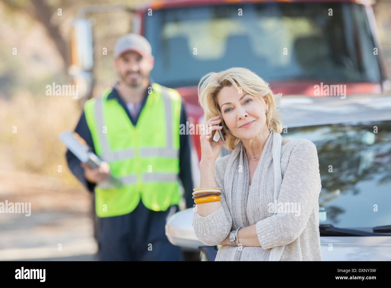 Am Straßenrand Mechaniker hinter Frau auf Handy Stockfoto