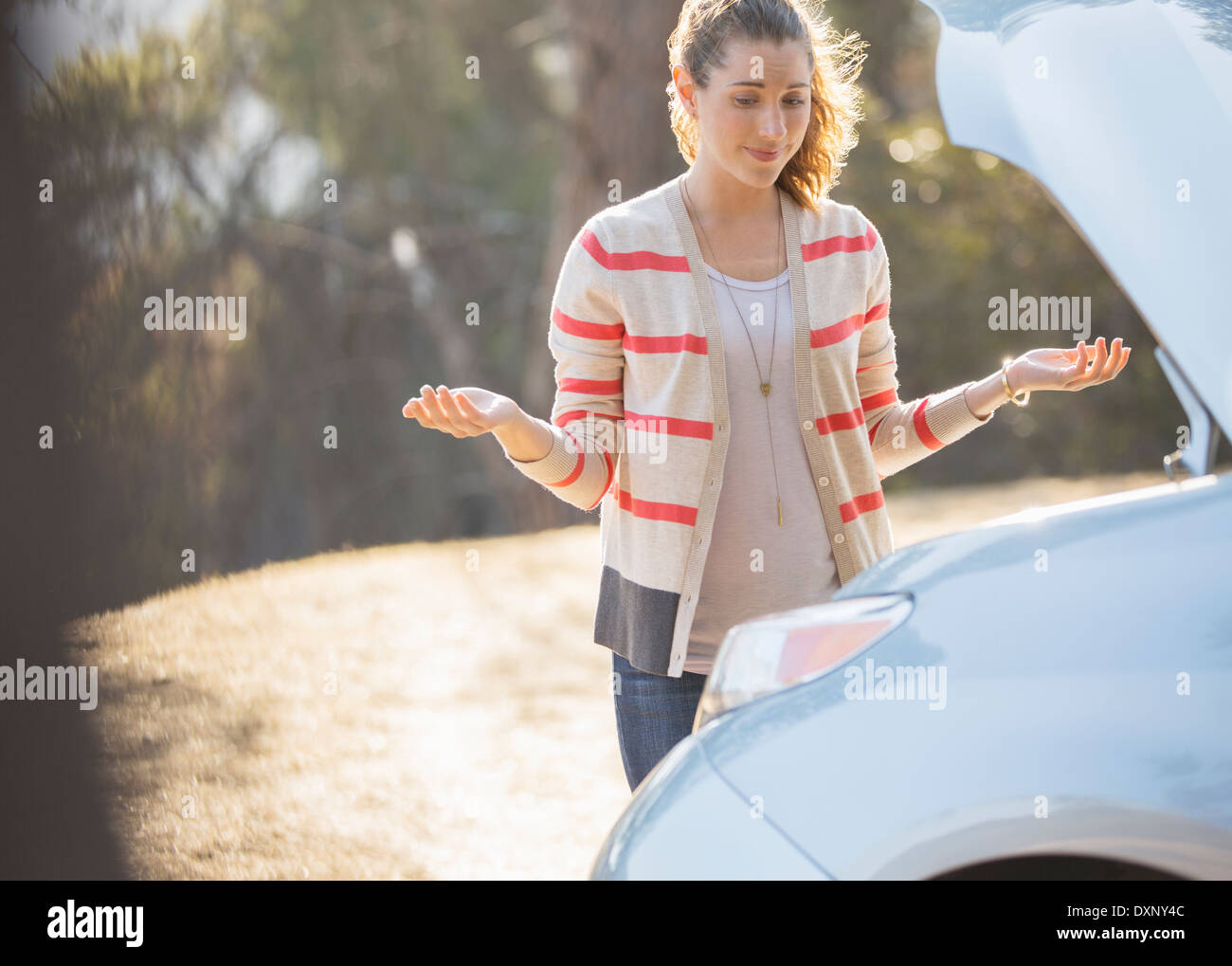 Frustrierte Frau betrachten Automotor am Straßenrand Stockfoto