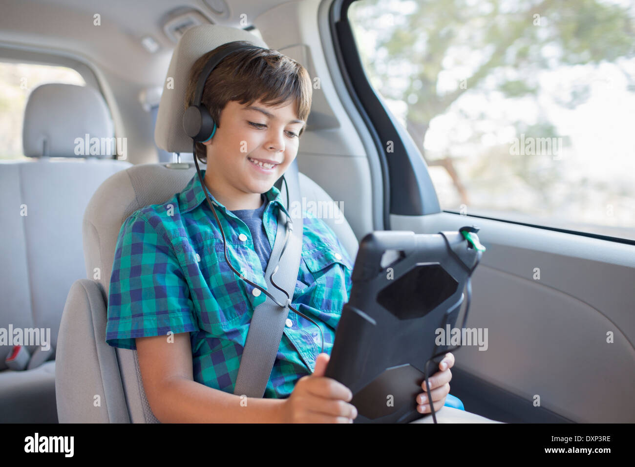 Fröhlicher Junge mit digital-Tablette im Rücksitz des Wagens Stockfoto