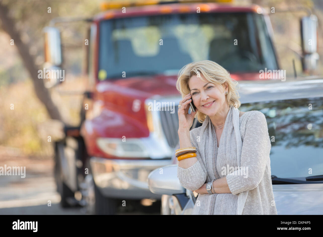 Frau am Handy in der Nähe von Abschleppwagen am Straßenrand Stockfoto