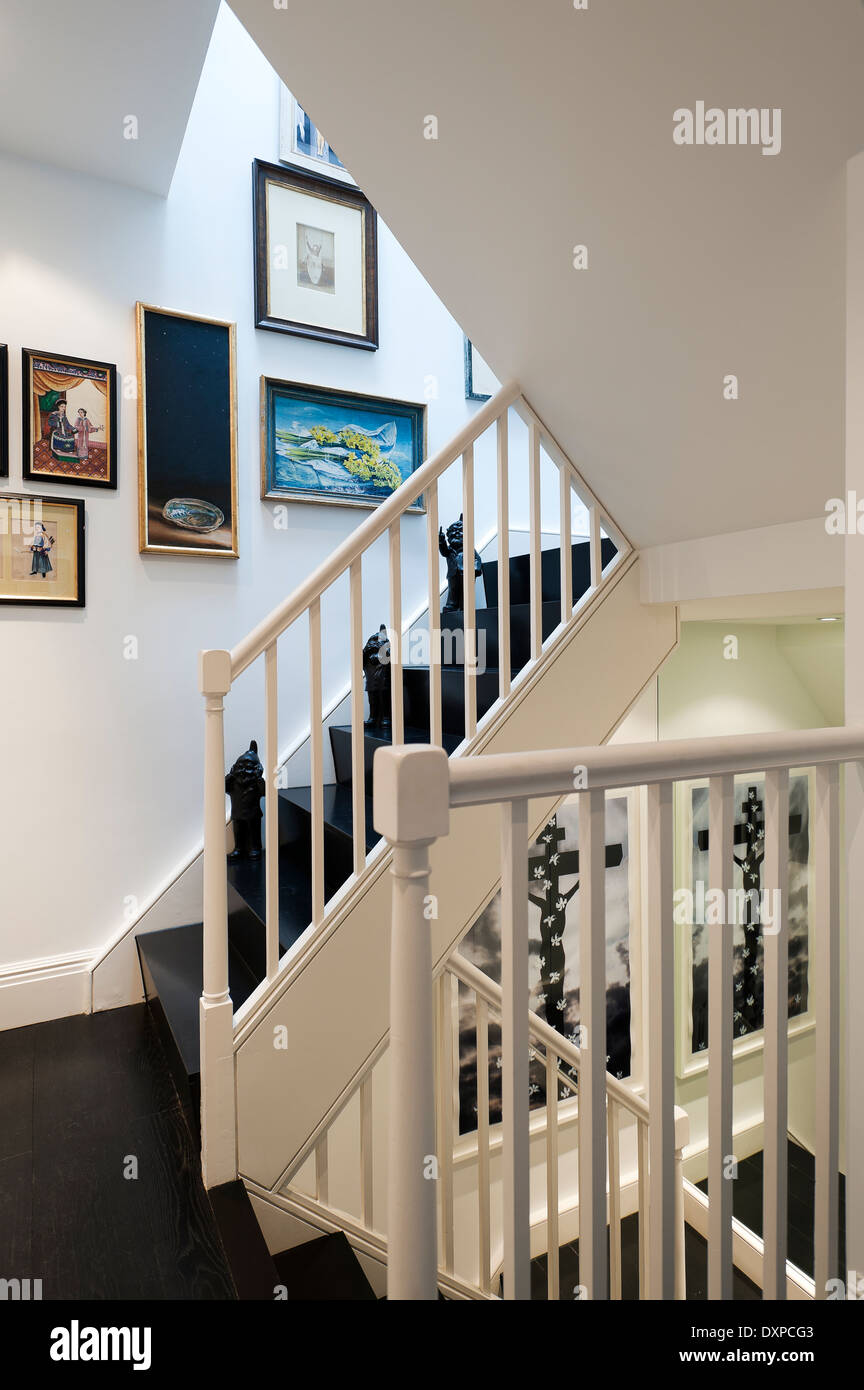 Schwarze Treppe mit weißen Geländer und gemischte Kunst an den Wänden Stockfoto
