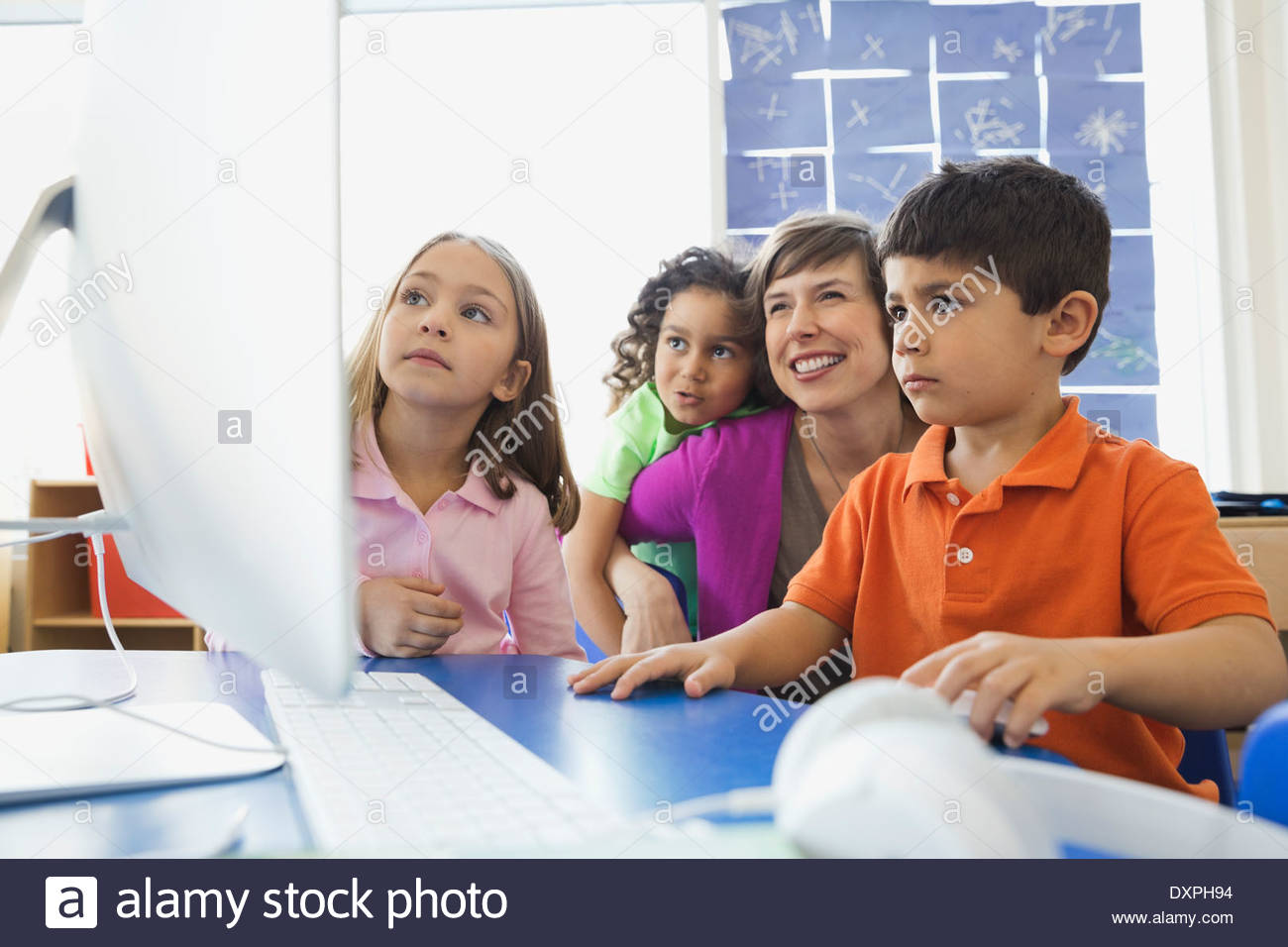 Lehrer und Kinder bei der Nutzung der Computer in der Grundschule Klasse Stockfoto