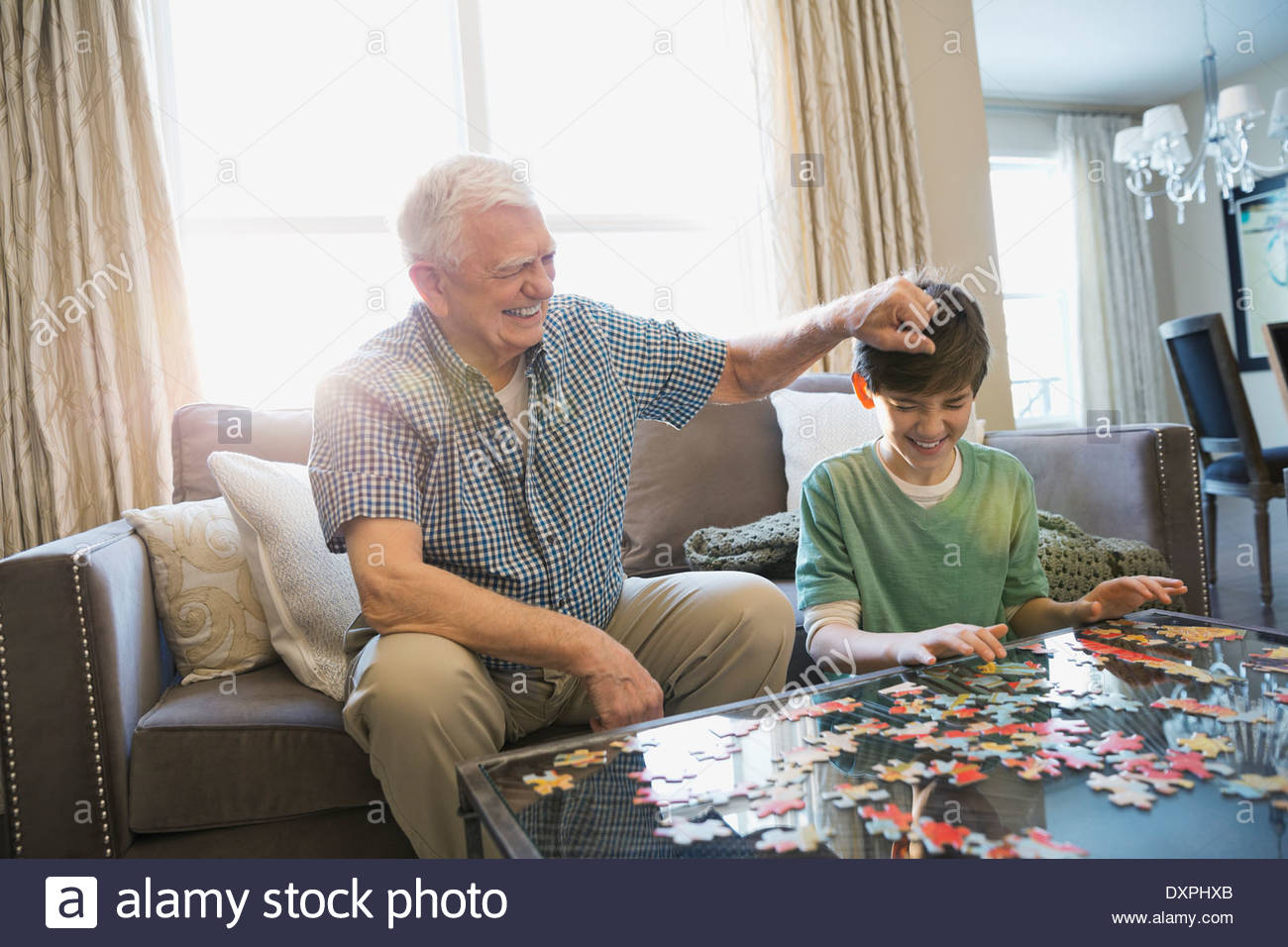 Spielerische Großvater und Enkel lösen Rätsel zu Hause Stockfoto