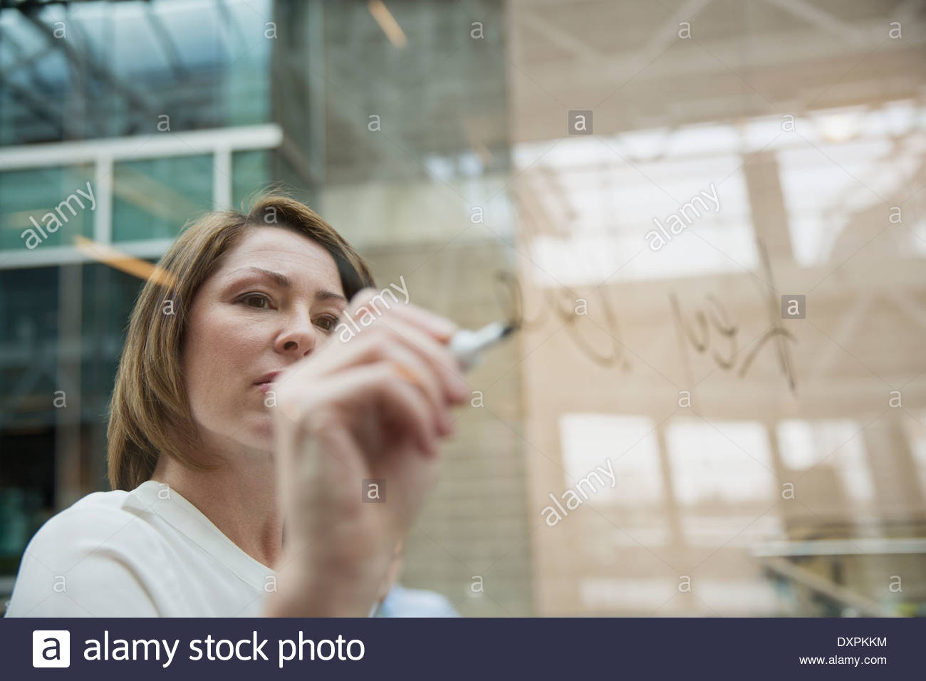 Geschäftsfrau mit trocken abwischbaren Marker schreiben auf Glas Stockfoto