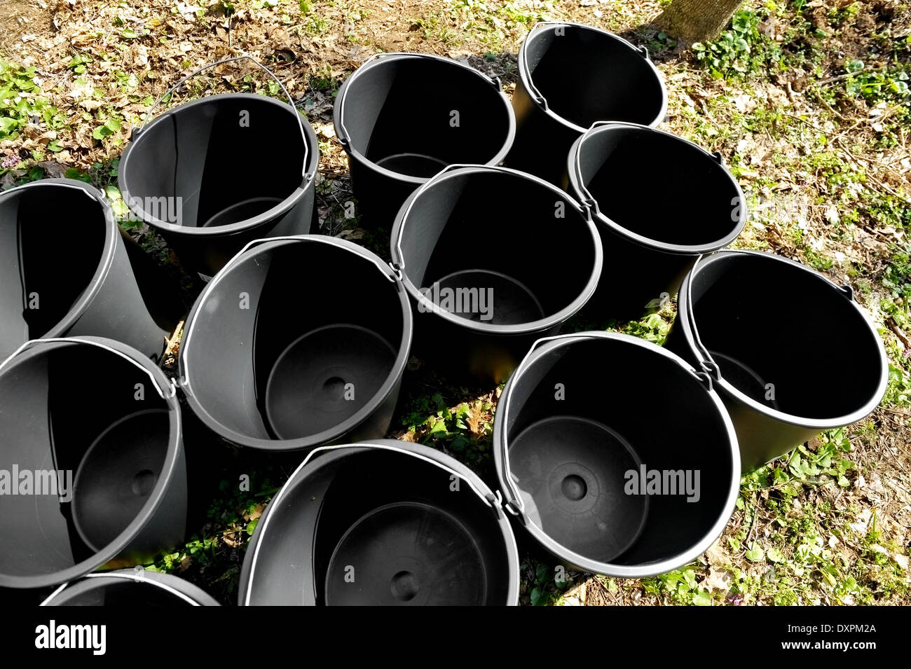 Mehrere leere schwarze Gärtnerei Eimer auf dem Boden Stockfoto