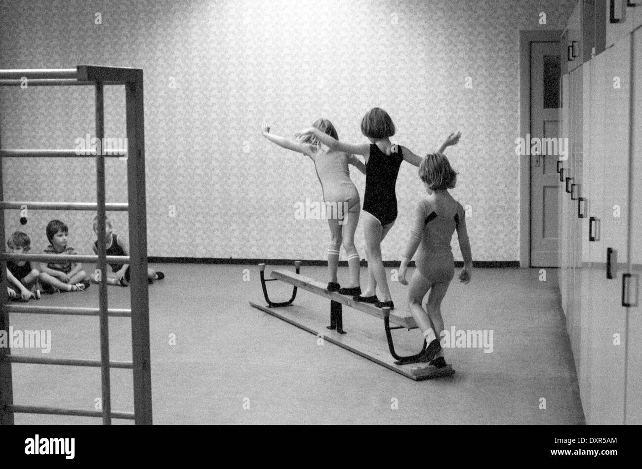 Berlin, DDR, kleinen Kindern Gleichgewicht im Sportunterricht in einer umgedrehten Bank Stockfoto