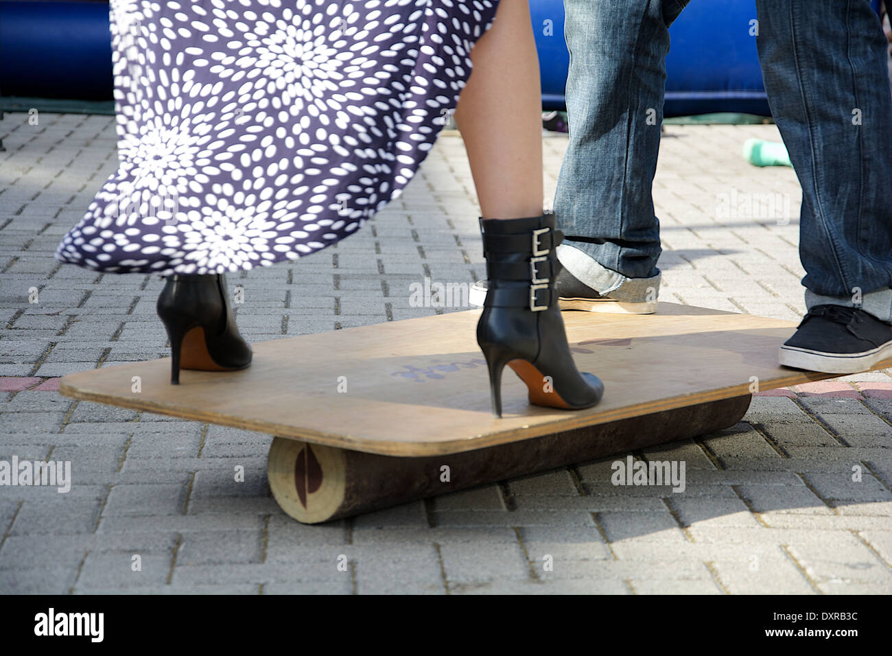 Erwachsener Mann und Frau mit high Heels balancieren auf einem hölzernen Balance Board auf dem Festival Internacional de Diseno Stockfoto