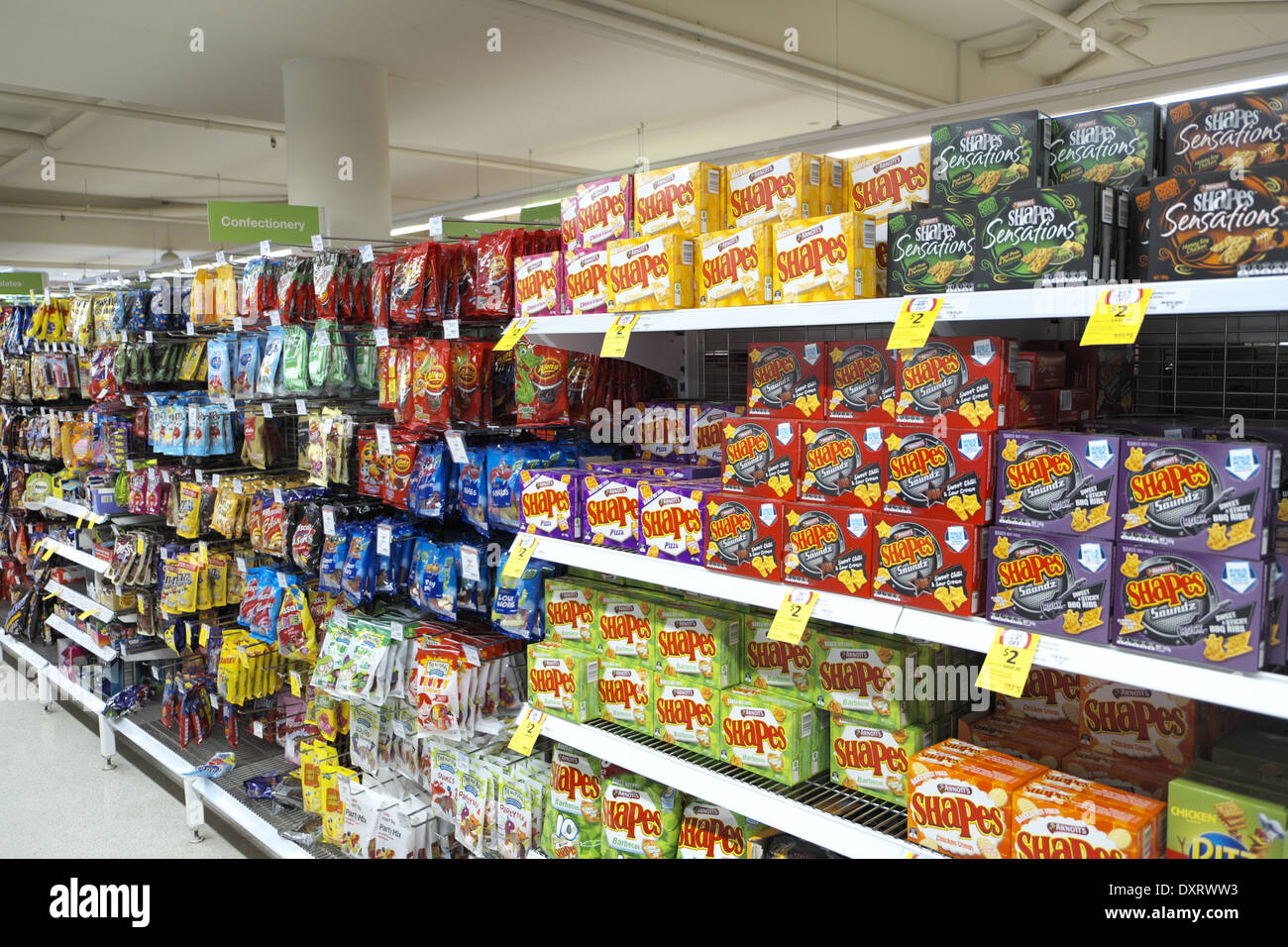 Stapelbare Regale in einem Coles Supermarkt in Sydney, NSW, Australien, wo Kekse, Süßigkeiten und Süßwaren verkauft werden Stockfoto