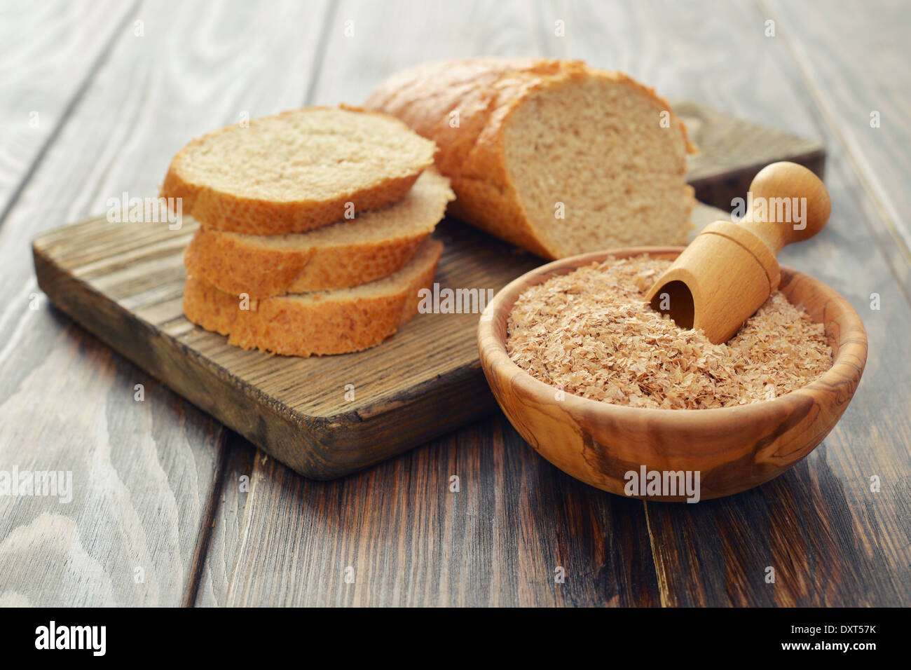 Weizenkleie in Schüssel mit geschnittenem Brot auf hölzernen Hintergrund Stockfoto