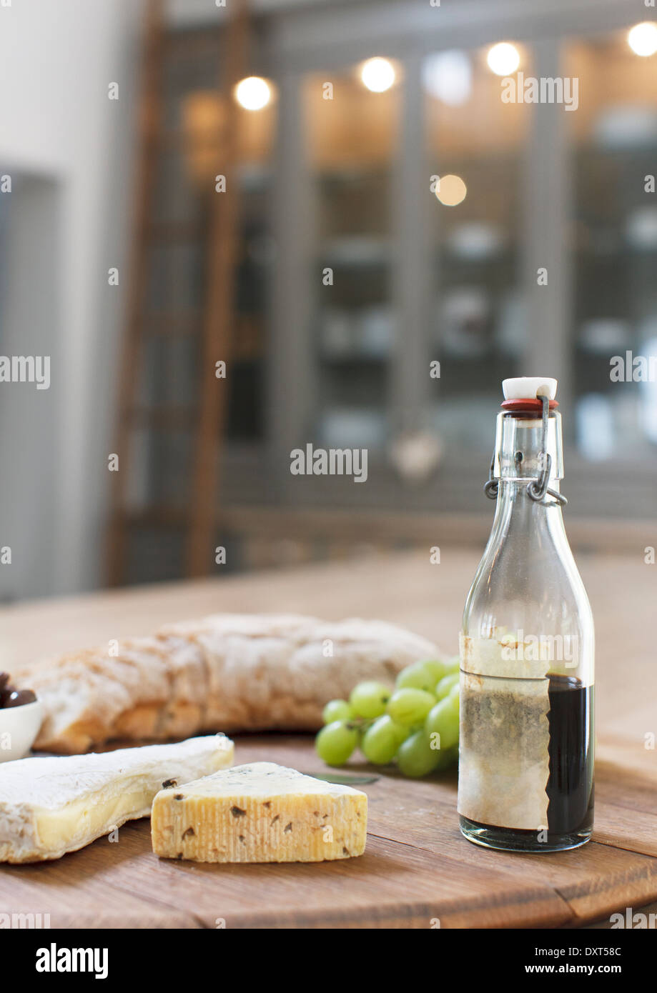 Balsamico-Essig, Trauben, Käse und Baguette auf Holzbrett Stockfoto