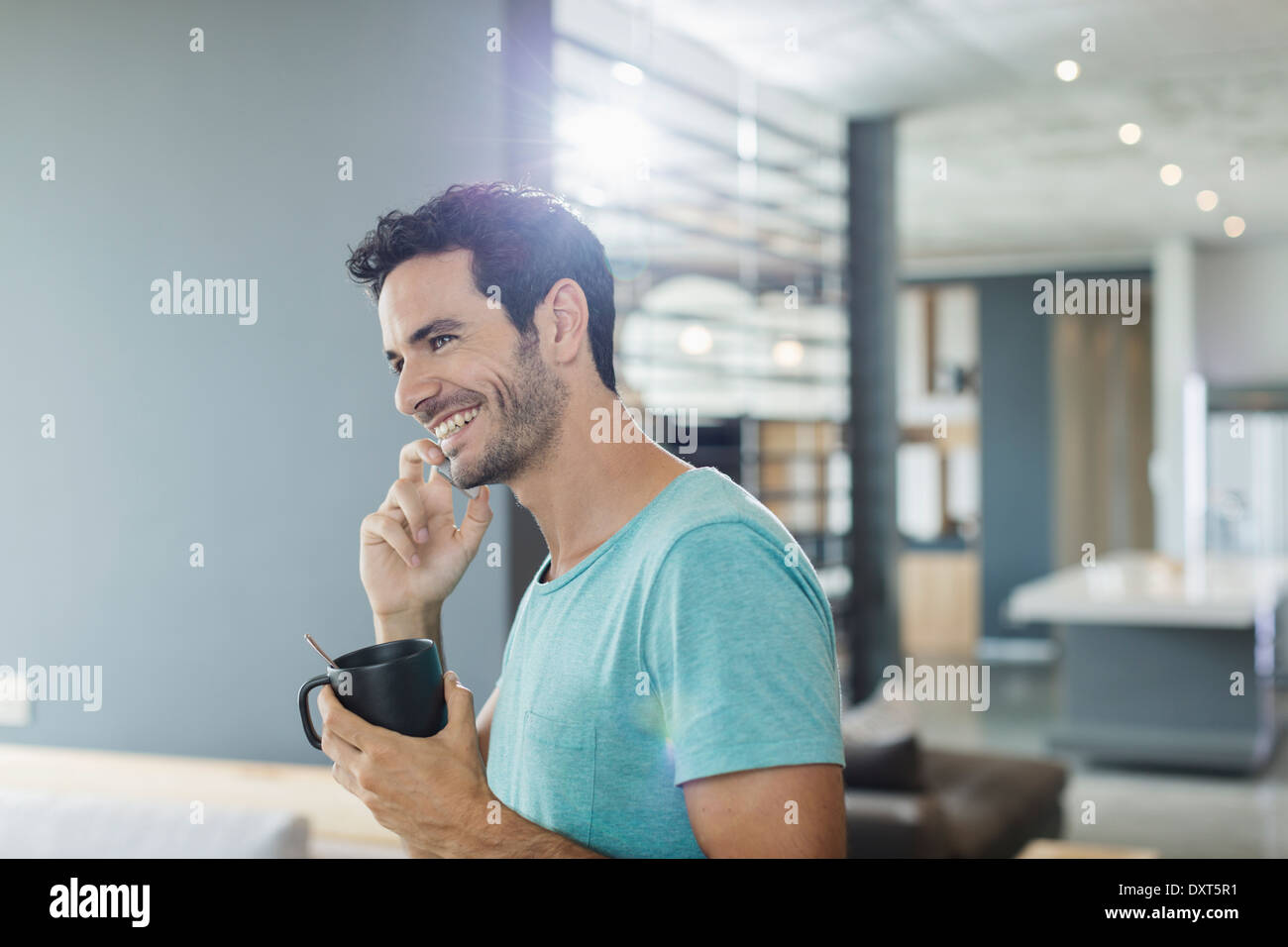 Glücklicher Mann reden über Handy und Kaffeetrinken zu Hause Stockfoto