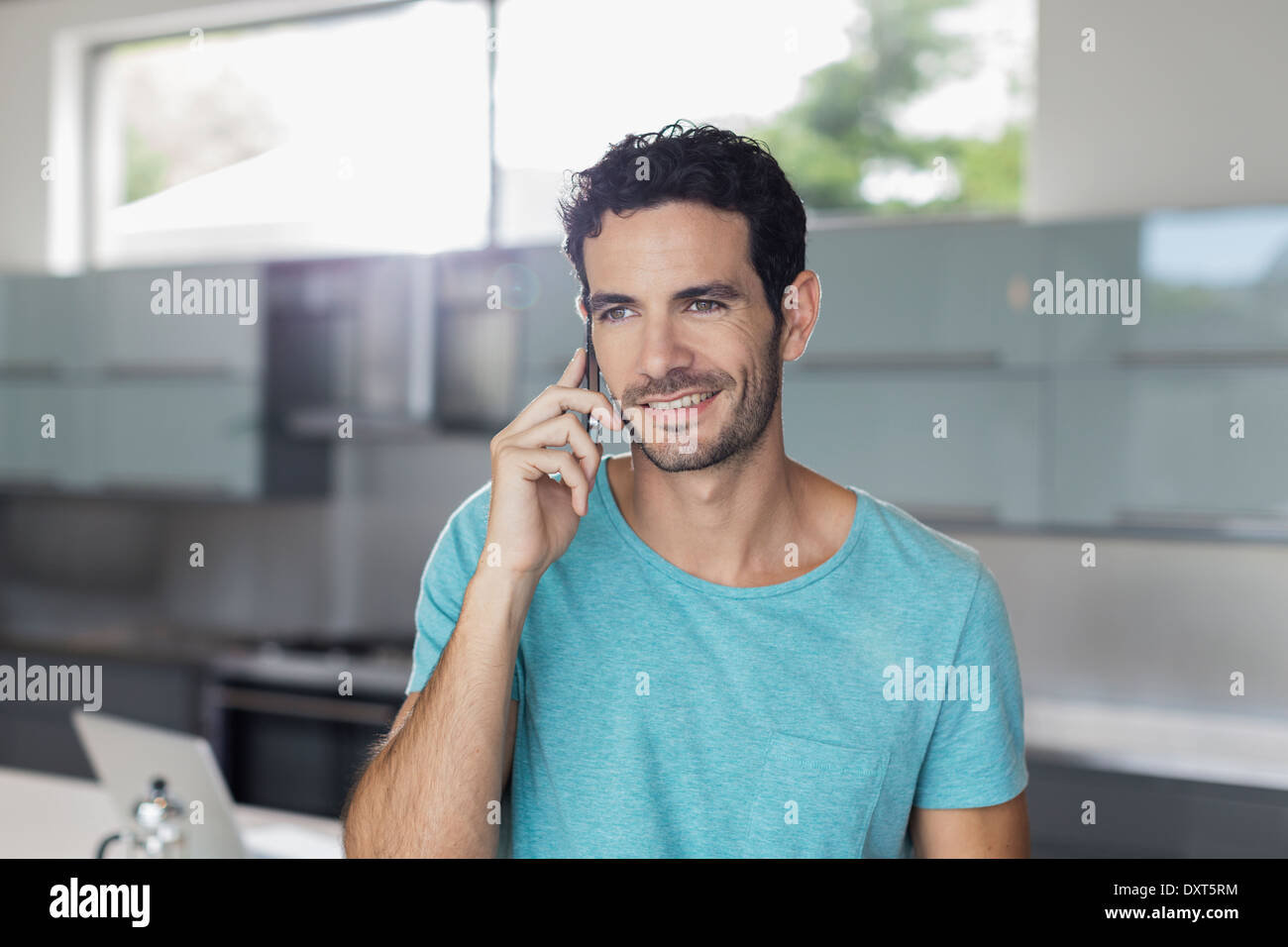 Lächelnder Mann reden über Handy in Küche Stockfoto