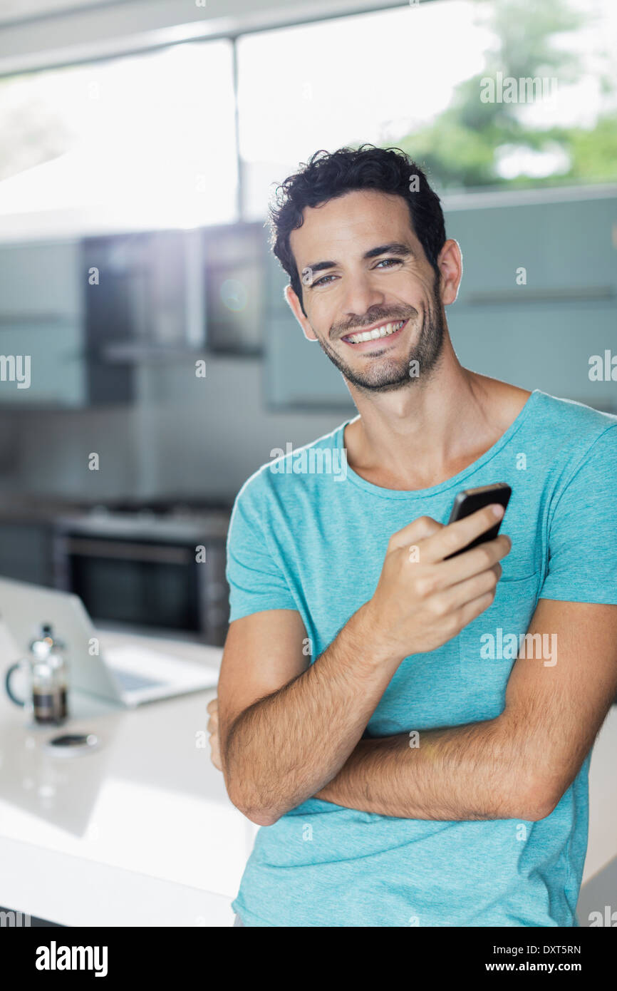 Porträt von lächelnden Mann mit Handy in Küche Stockfoto