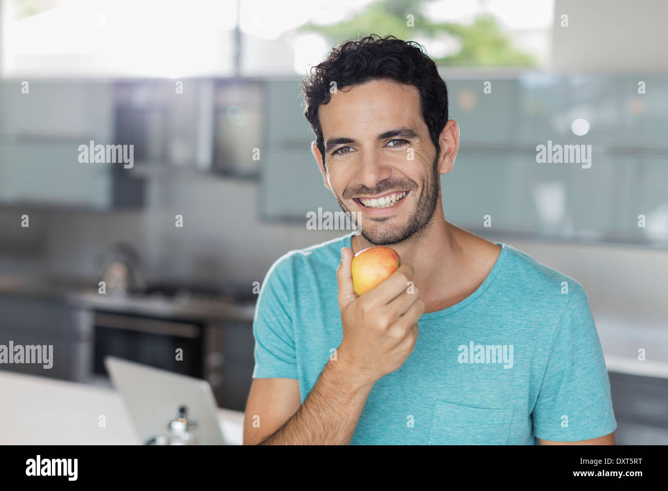 Porträt von lächelnden Mann Essen Apfel in Küche Stockfoto