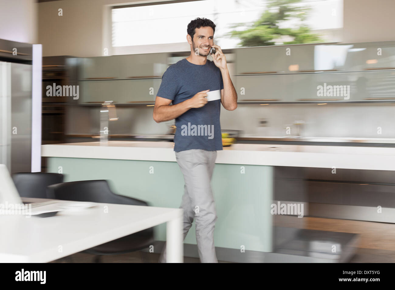 Lächelnder Mann Kaffee trinken und reden über Handy in Küche Stockfoto