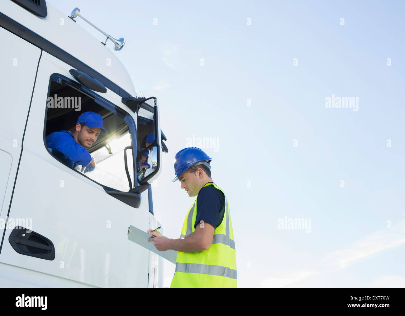 Arbeiter mit Zwischenablage im Gespräch mit LKW-Fahrer Stockfoto