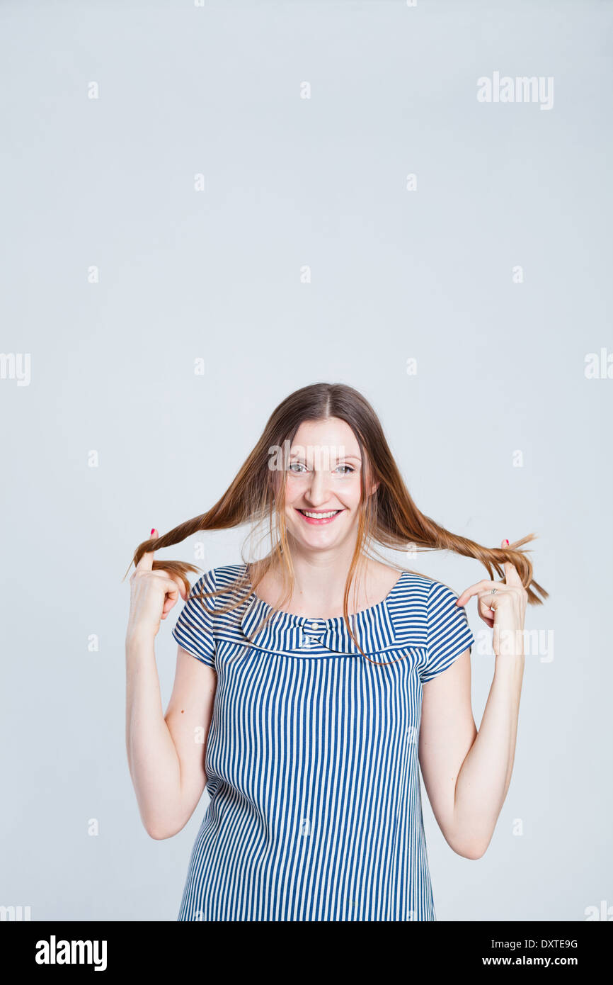 Studio-Porträt des Lächelns attraktive und stilvolle Frau halten Haare in den Fingern Stockfoto
