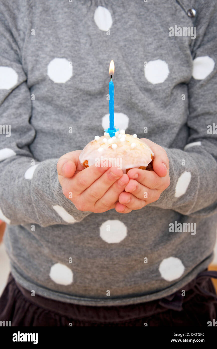 Kind am Geburtstag Party halten Cupcake mit brennende Kerze, München, Bayern, Deutschland Stockfoto