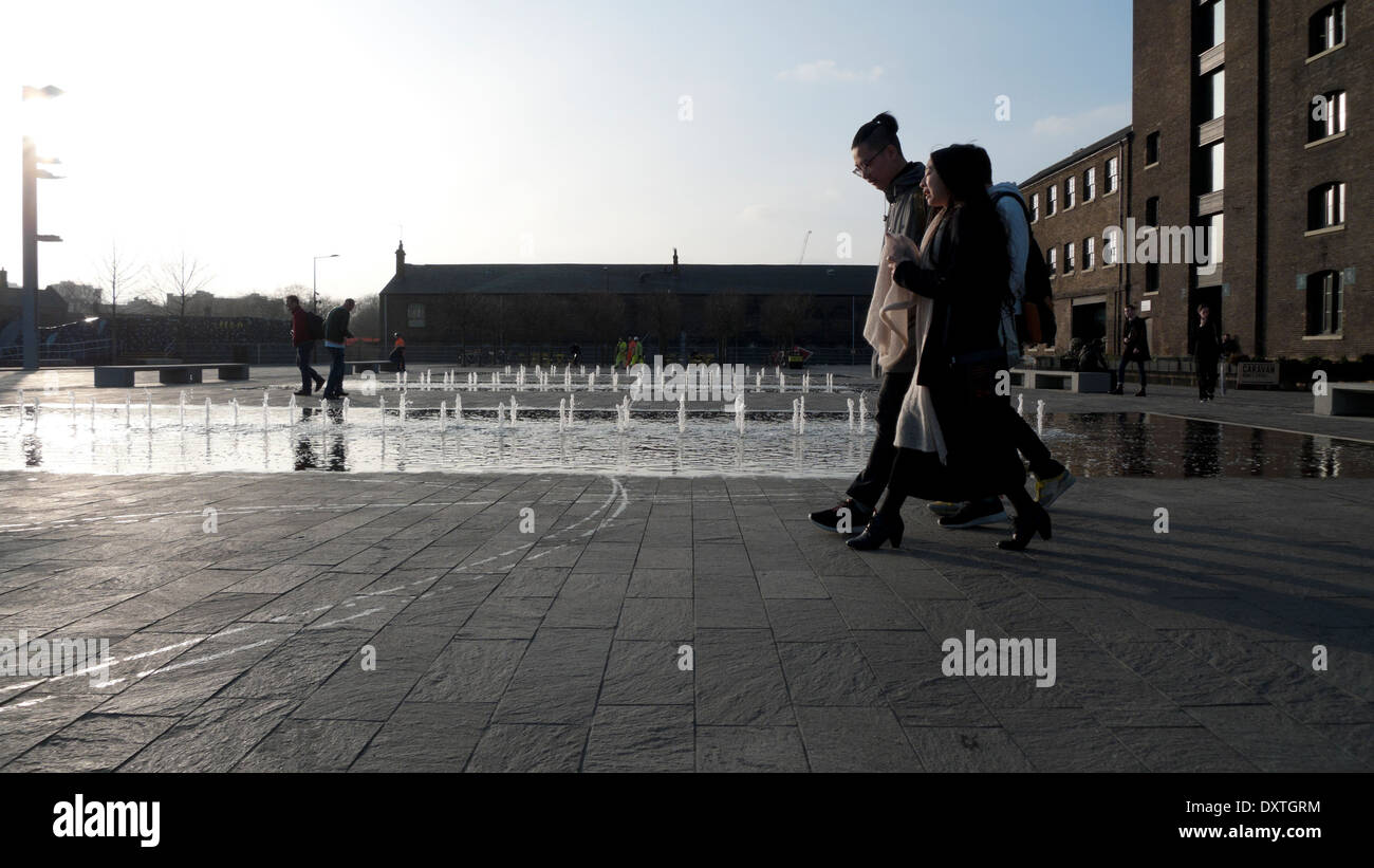 Schüler zu Fuß vorbei an Brunnen außerhalb UAL Central St Martins Kunsthochschule in Granary Square, Kings Cross London N1 KATHY DEWITT Stockfoto