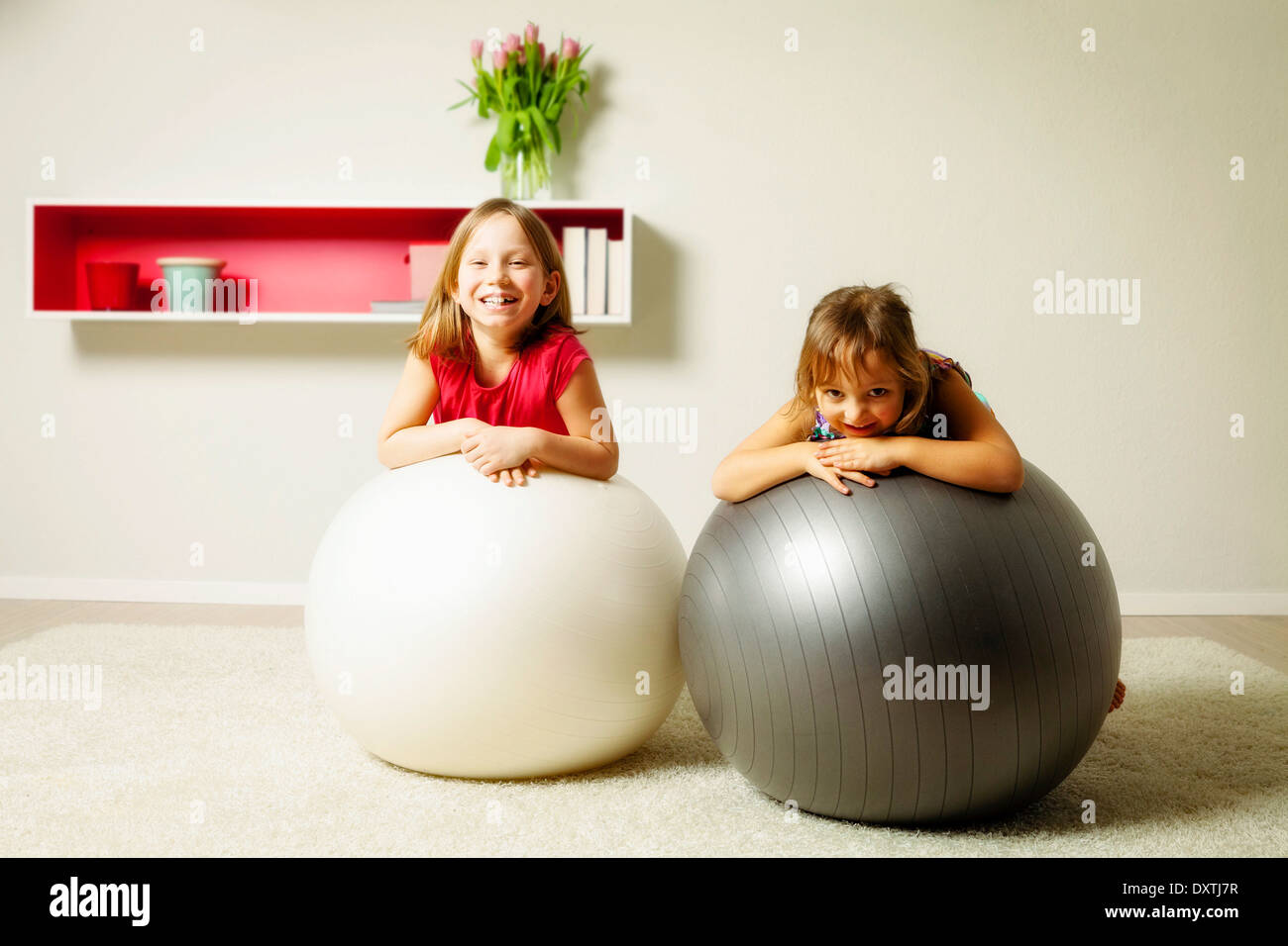 Kinder im Wohnzimmer spielen mit springenden Bällen, München, Bayern, Deutschland Stockfoto