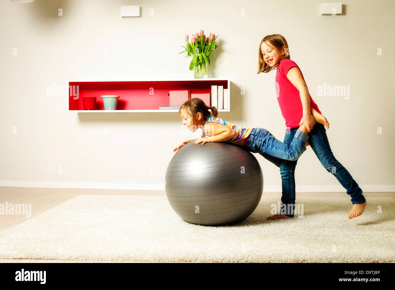 Kinder im Wohnzimmer spielen mit springenden Bällen, München, Bayern, Deutschland Stockfoto